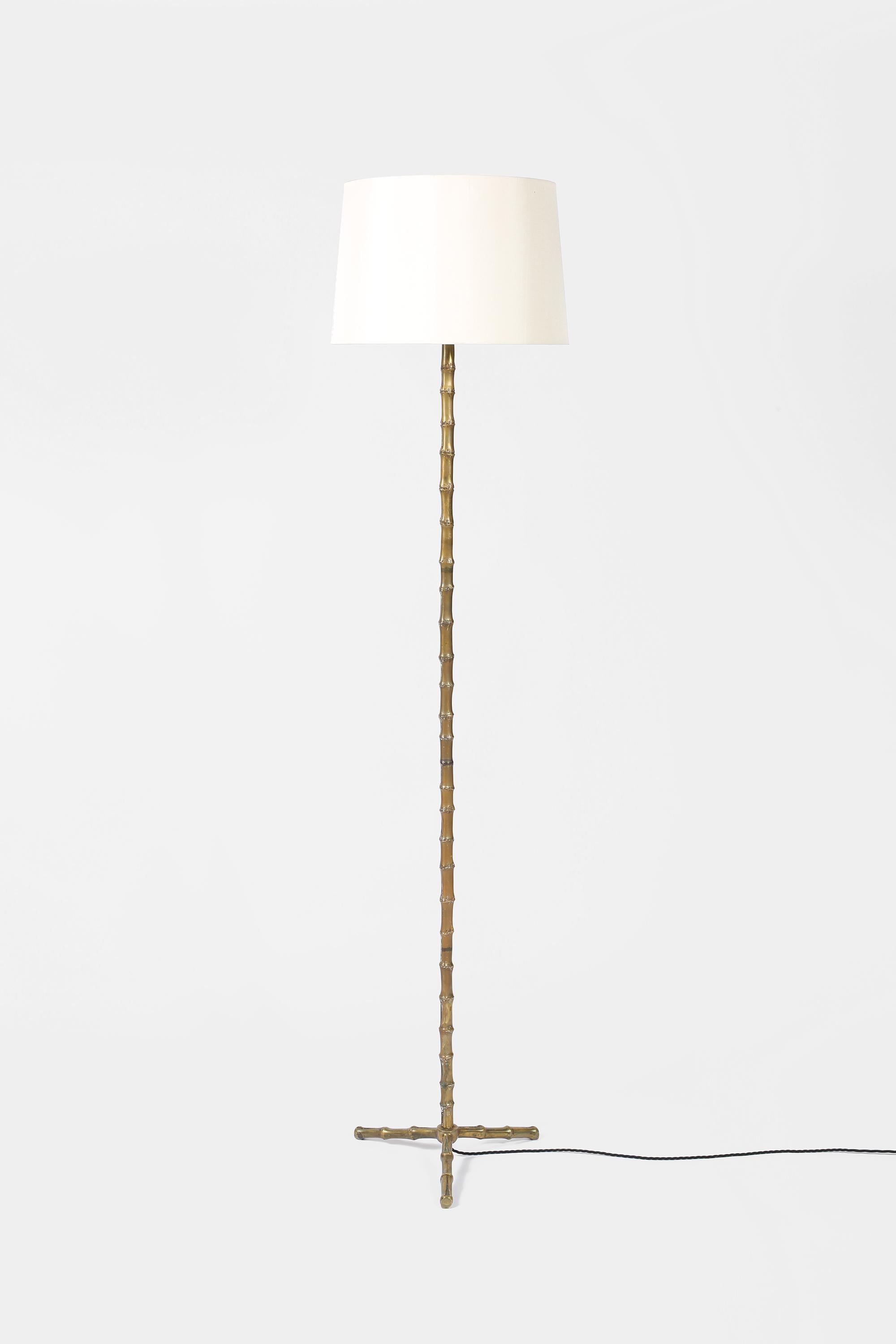 A solid bronze floor lamp with stylised faux bamboo stem and three point base attributed to Maison Bagues. French, c. 1950s. Supplied with an off-white dupion silk shade.