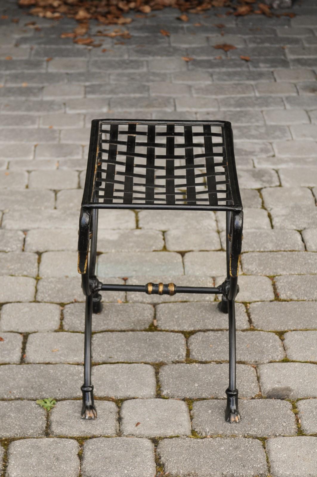 A vintage French metal curule Maison Jansen style stool from the mid 20th century with swan motifs and paw feet. This exquisite French stool features a rectangular latticed seat, beautifully supported by four graceful swan heads. The elegant base is