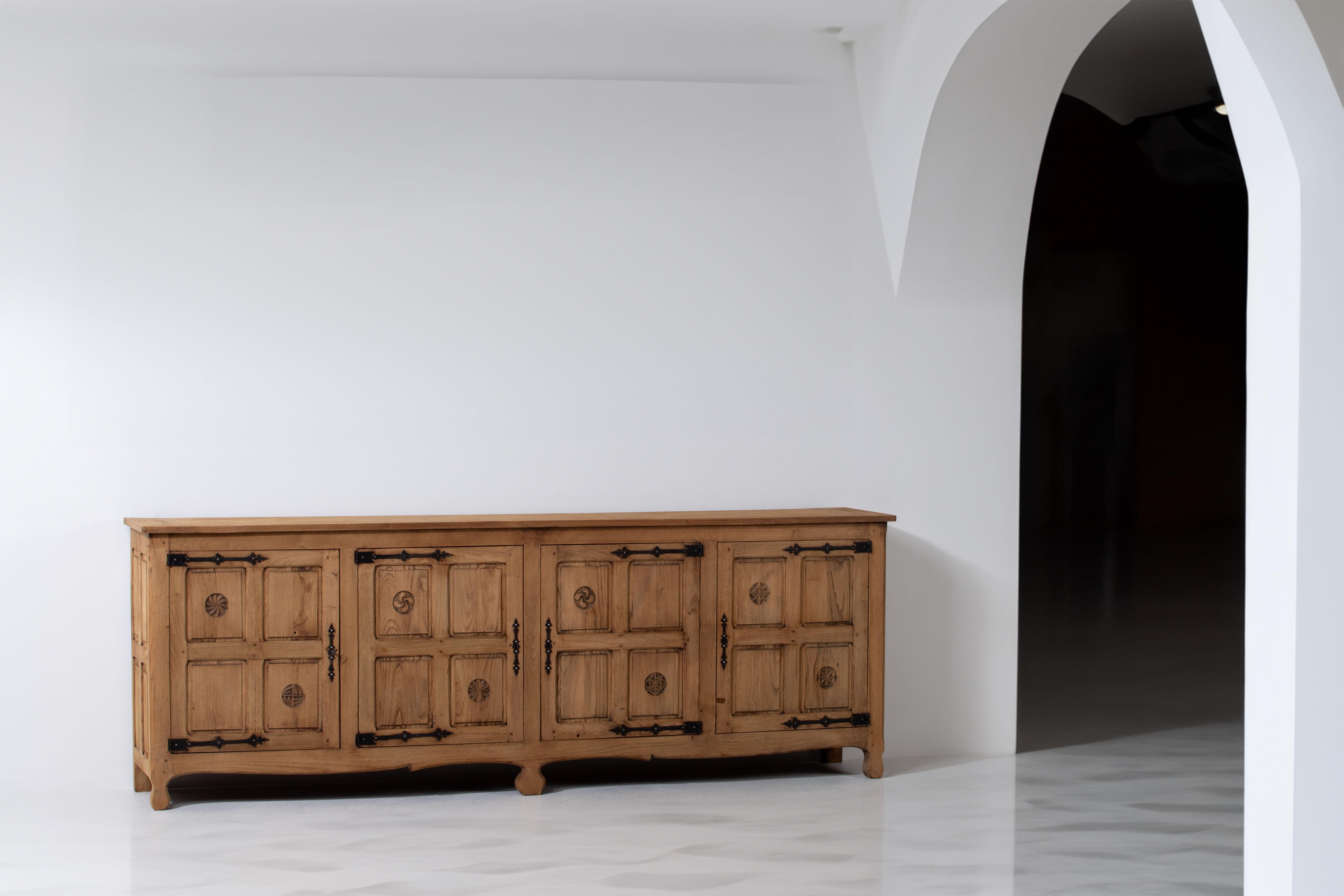 This magnificent oak sideboard originates from France and dates back to the elegant era of the 1950s. Its exquisite craftsmanship is unveiled through intricate carved panels on both sides and doors, truly showcasing the skill and artistry of French