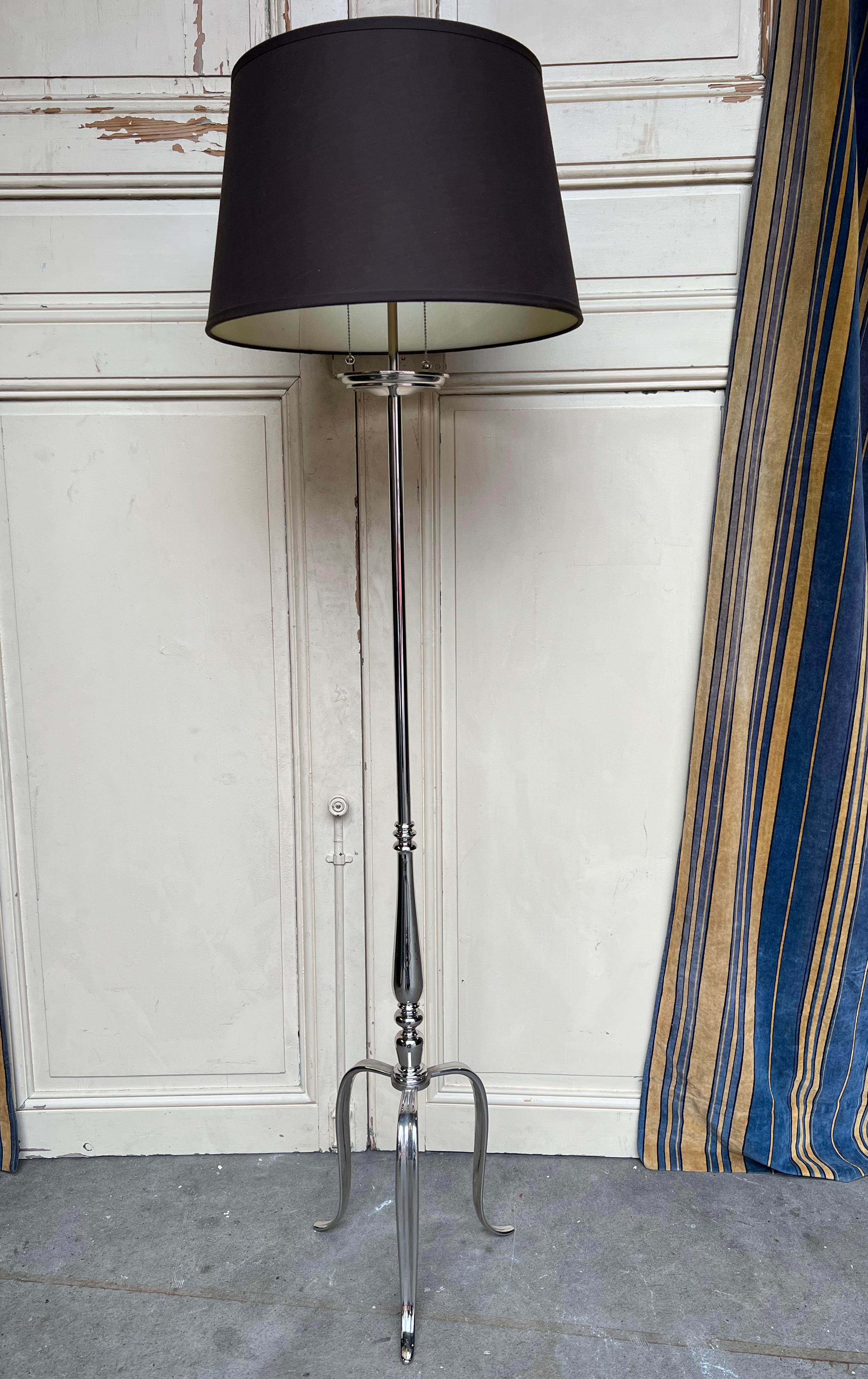 This elegant French mid-century modern brass floor lamp from the 1950s has  a lustrous polished nickel finish, adding a touch of sophistication. Supported by a tripod base, the lamp features turned bronze accents and a beautiful bobeche. It has been