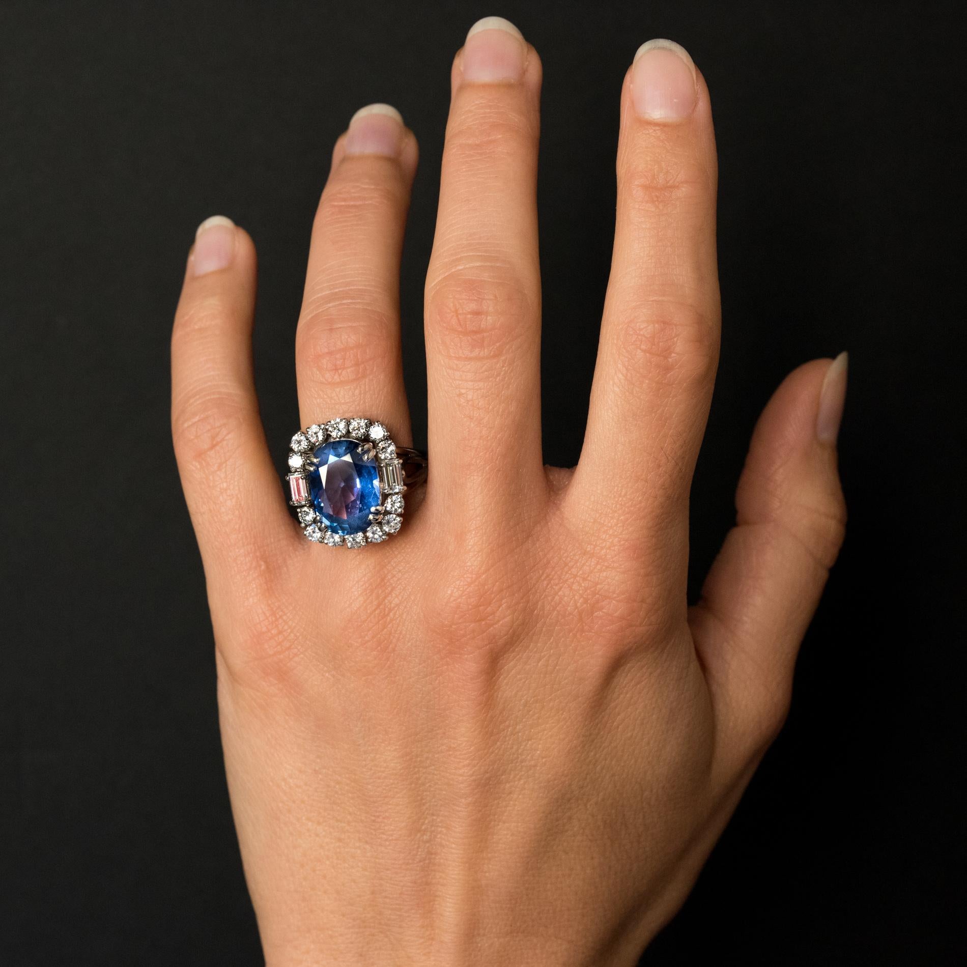 Ring in platinum, dog's head hallmark.
Important rectangular shape antique ring, it is set with 4 double claws, of an oval blue sapphire surrounded by 2 x 7 brilliant- cut diamonds and shouldered with 2 baguette diamonds. The ring consists of wires