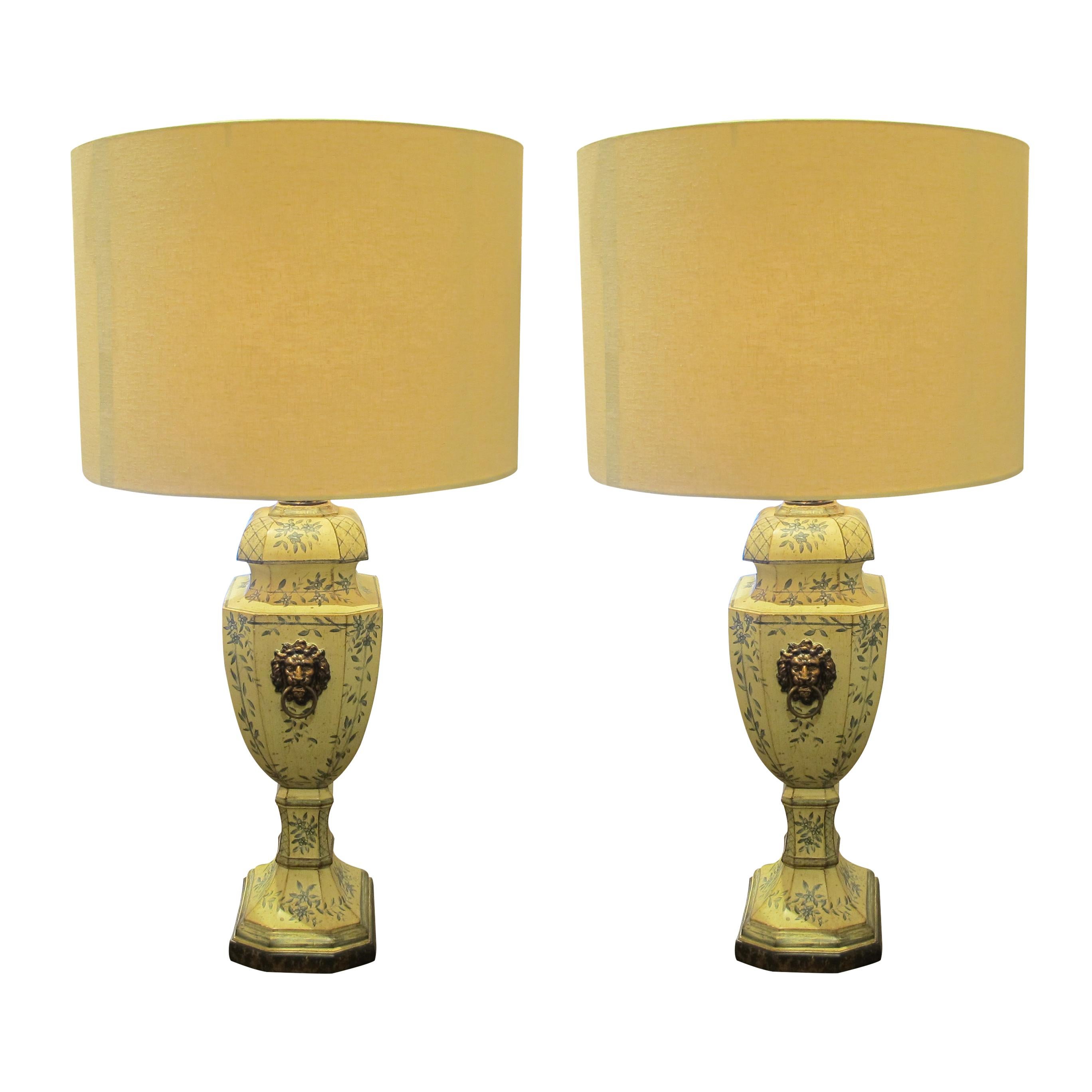 Pair of elegant mid-century French hand-painted toleware table lamps with bronze coloured lion heads with a ring on either side of the lamps. The lamps have a pale cream patina and are decorated with light blue hand-painted leaves, flowers, and