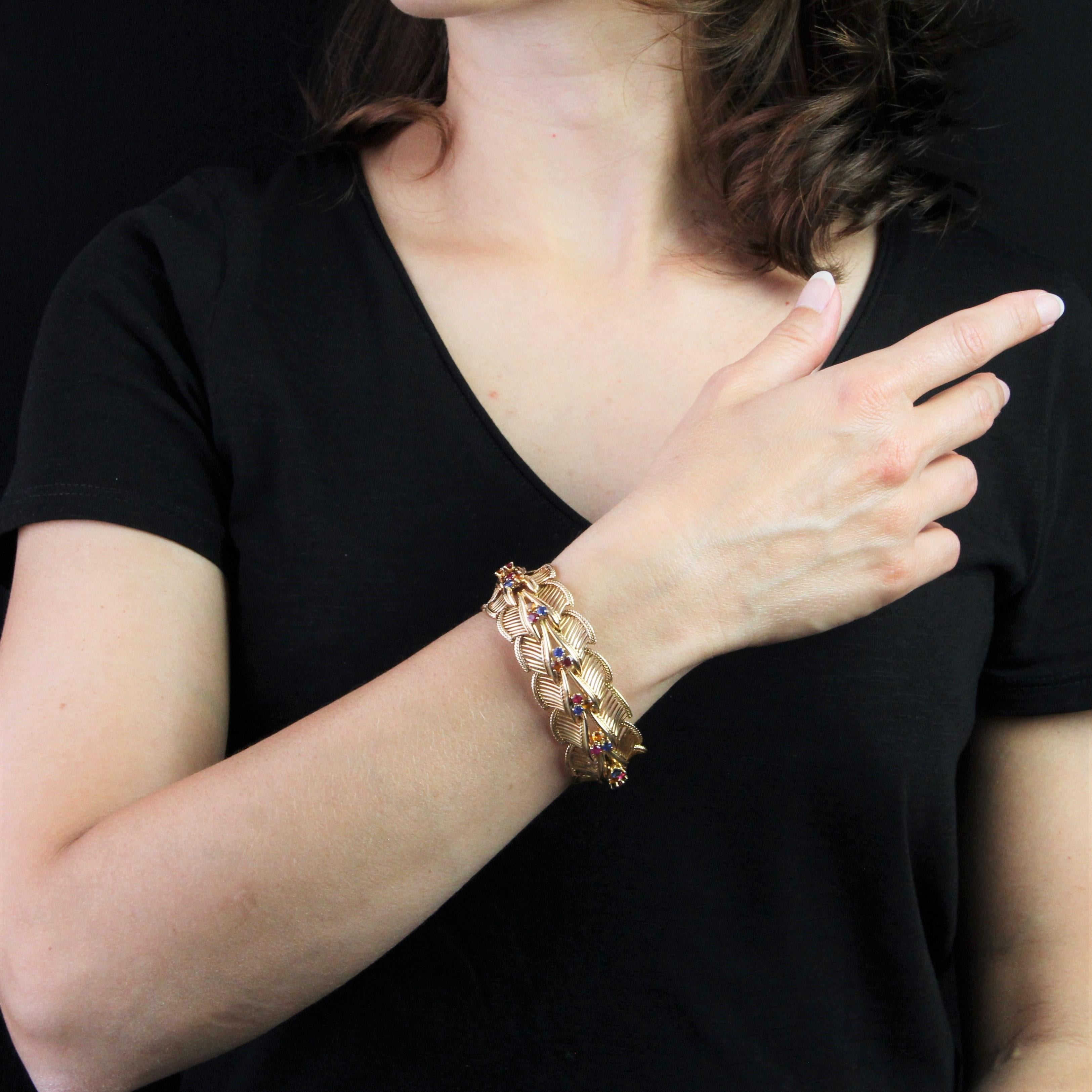 Armband aus 18 Karat Roségold, Eulenpunze.
Das imposante Retro-Armband besteht aus einer Reihe von Mustern aus durchbrochenen Goldfäden und Goldkordeln, die jeweils mit 3 Steinen verziert sind: Rubinen, Saphiren und Zitrinen, die alle miteinander
