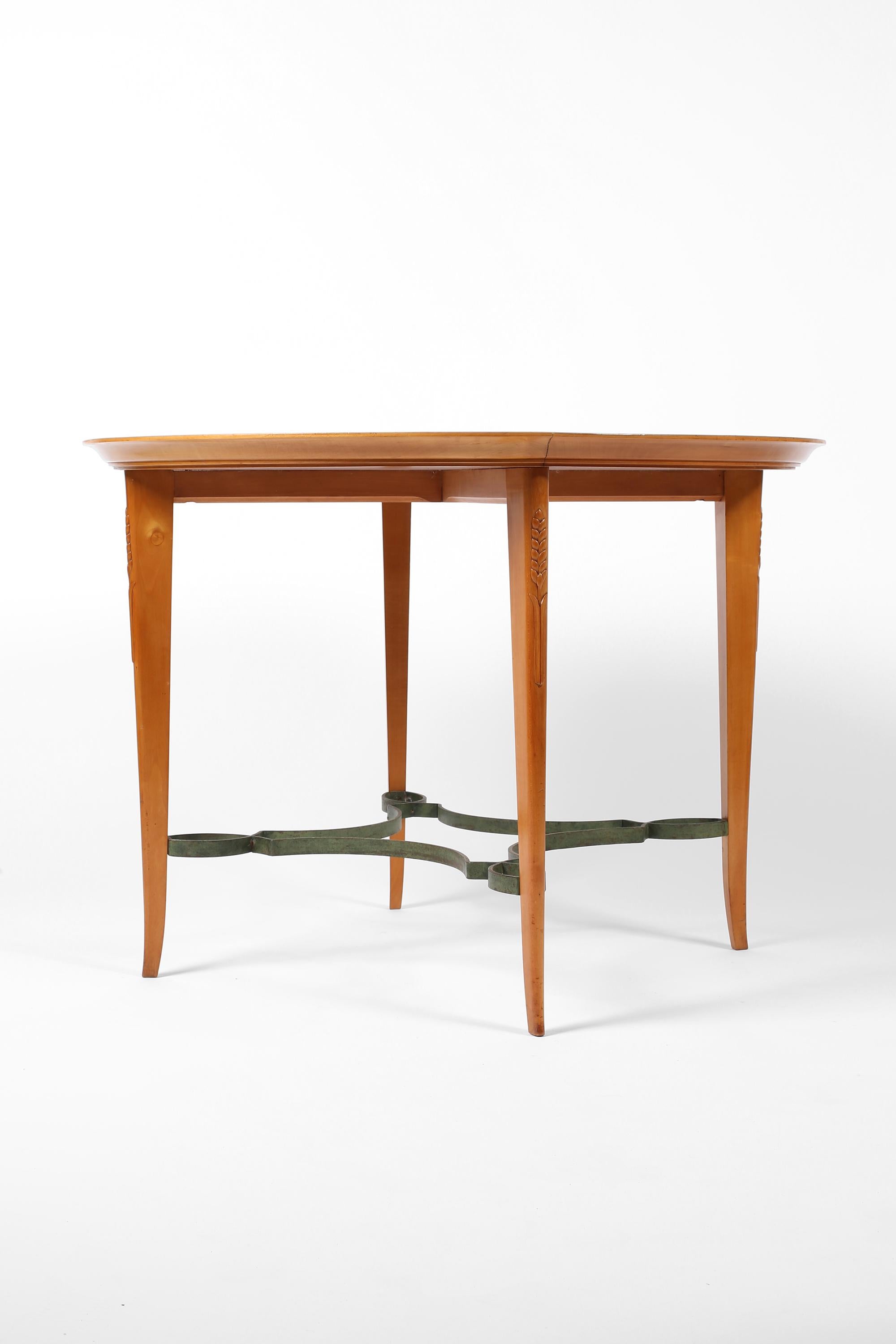 Une élégante table centrale circulaire en bois satiné attribuée à André Arbus (1903-1969). Le haut des pieds est orné d'épis de blé sculptés, et l'entretoise décorative en fer forgé est patinée d'un faux vert-de-gris. Français, c. 1950.