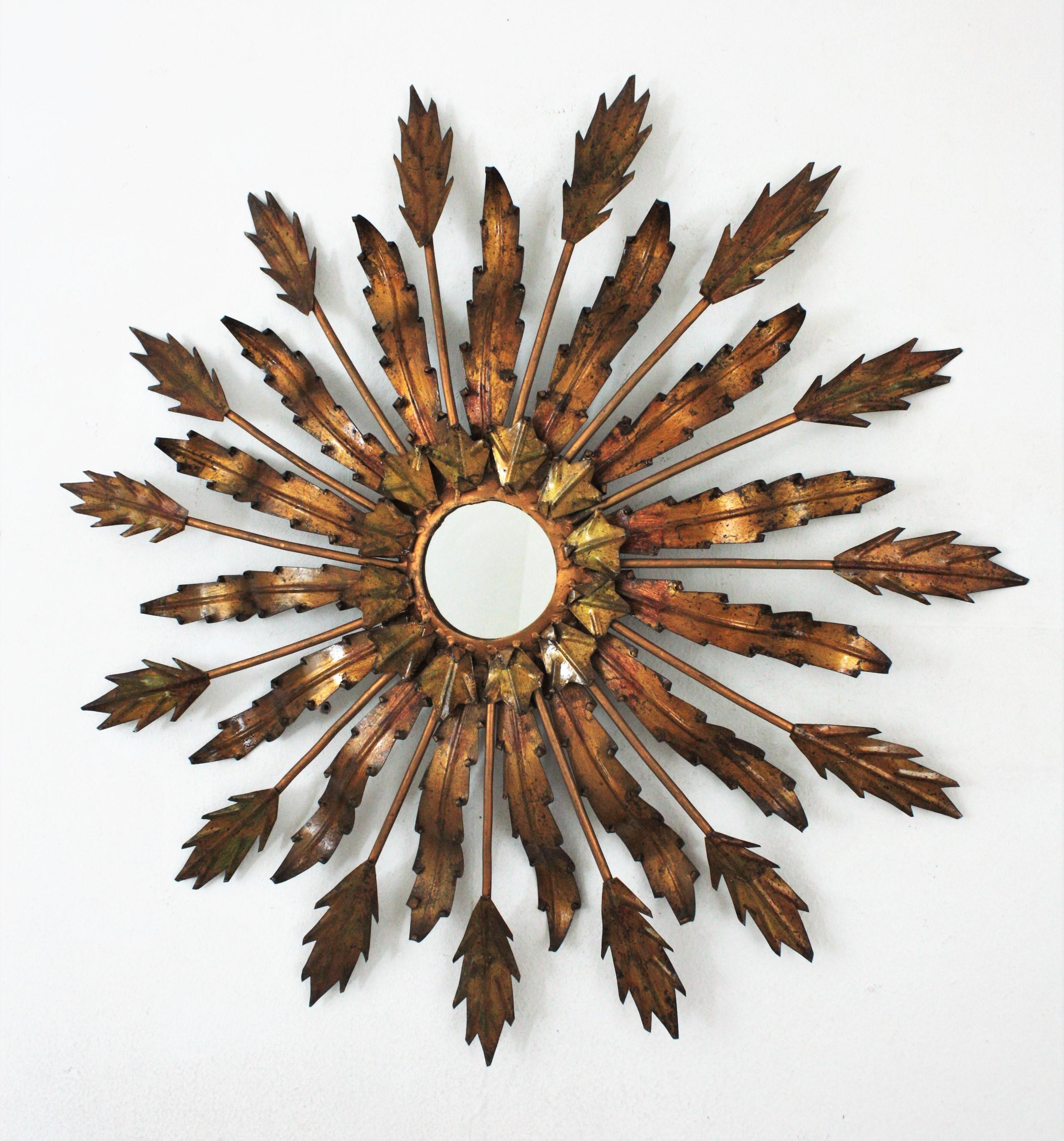A beautiful Brutalist hand-hammered gilt iron sunburst mirror with leafed design, France, 1950s.
Alternating leaves with different shapes surrounding a small corolla around the glass.
It has a dramatic aged patina in bronze-gold gilt iron with softs