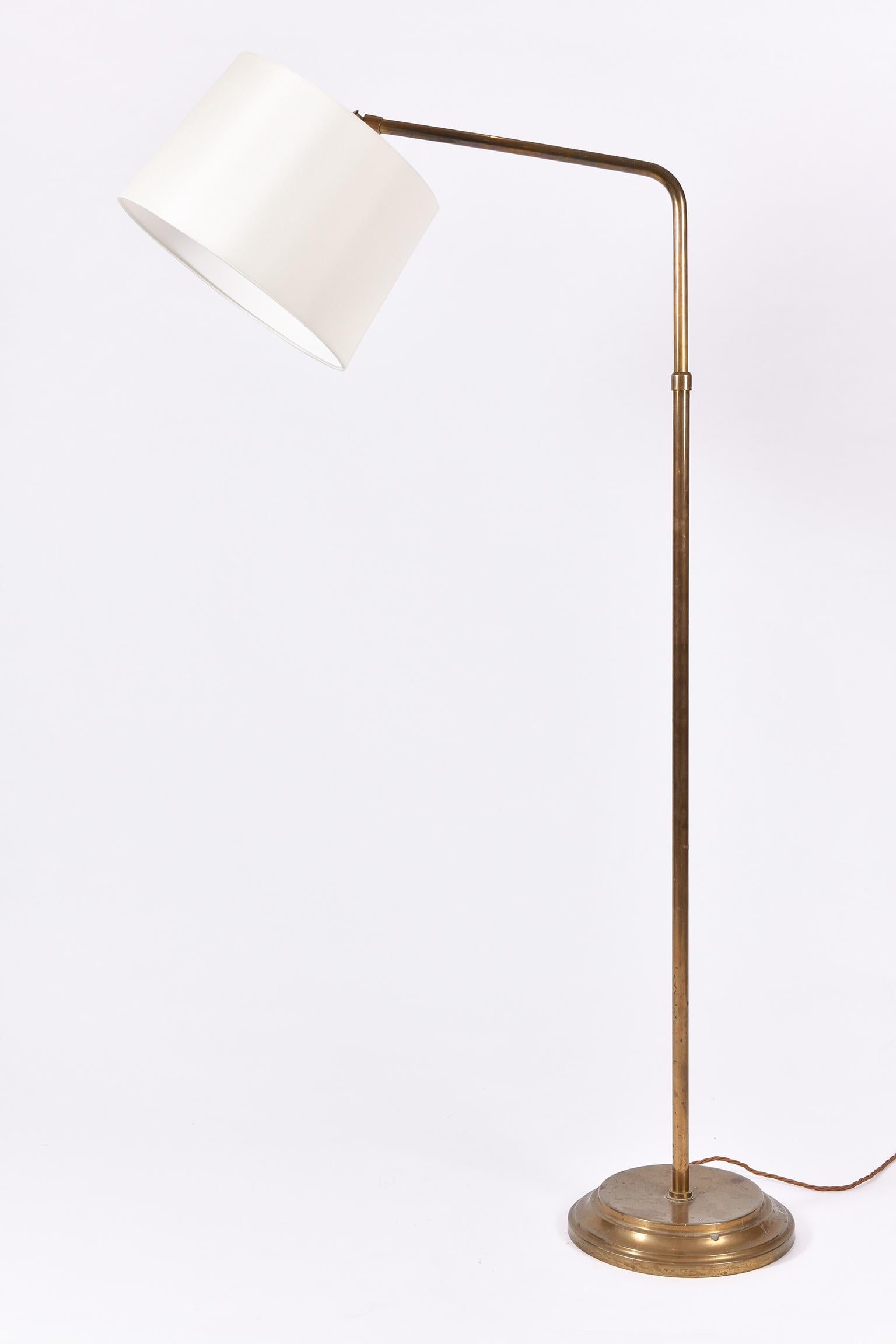 A patinated brass telescopic floor lamp, with an ivory tapered shade orientation adjustable
France, circa 1950.