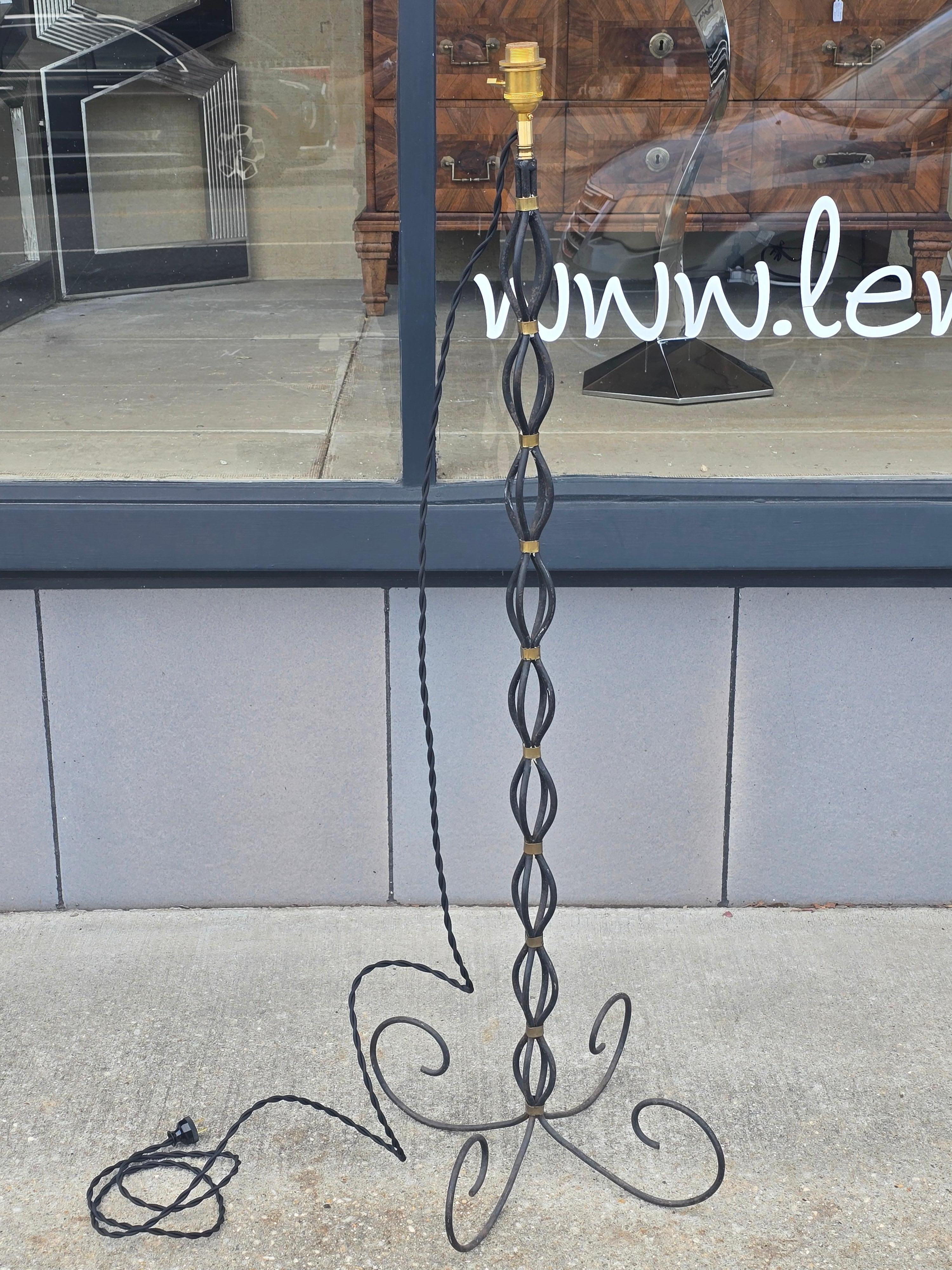 Una splendida lampada da terra francese in ferro battuto, anni '50, nello spirito inconfondibile di Jean Royère. La colonna è formata da aste di ferro intrecciate - aperte, attorcigliate e ritmicamente distanziate - tenute in posizione con collari