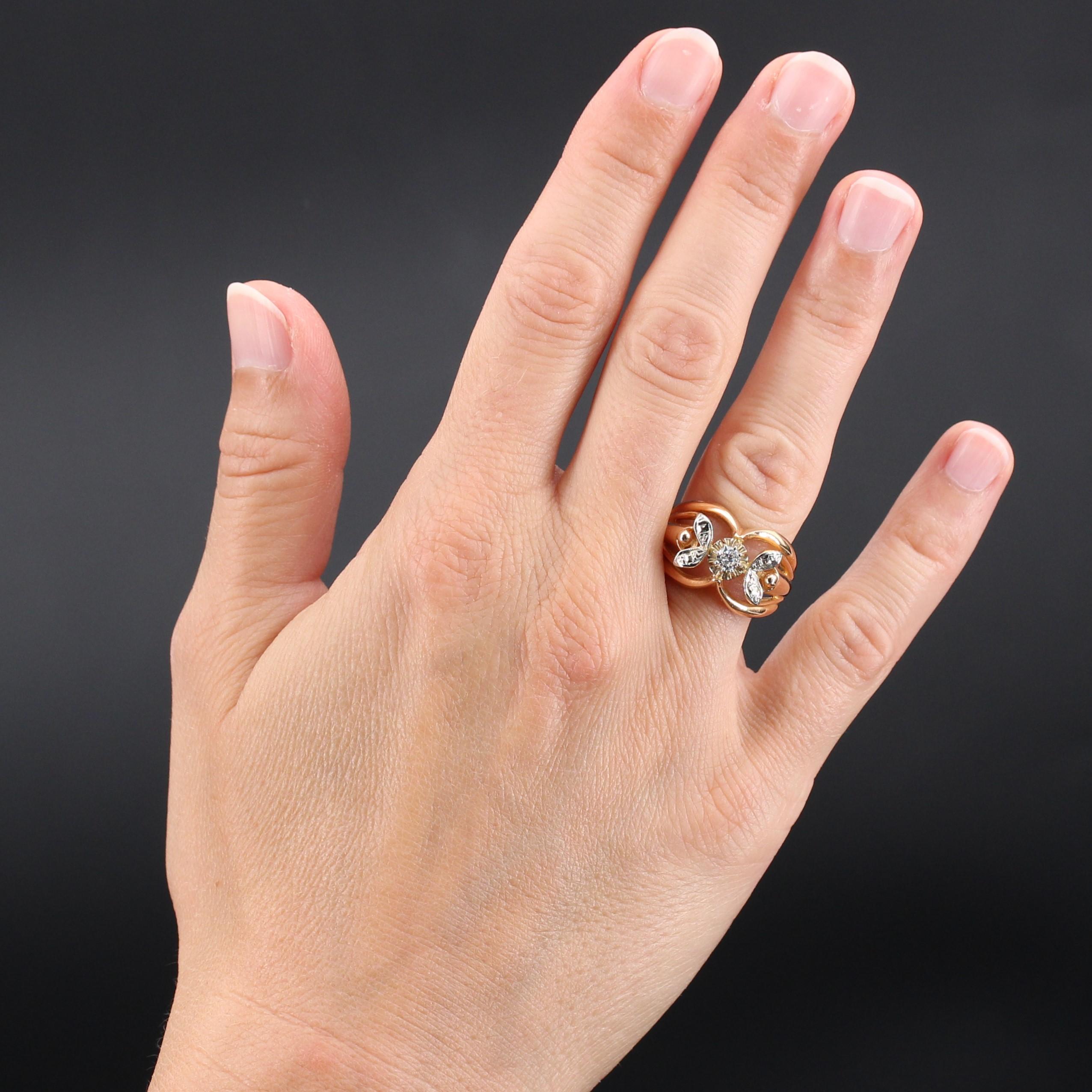 Anello in oro rosa e bianco a 18 carati, con marchio a testa d'aquila.
Sulla parte superiore sono incastonati 8 griffe di diamanti taglio brillante e 2 piccole foglie con 2 x 2 diamanti taglio rosa. L'anello è traforato con fili d'oro.
Peso totale