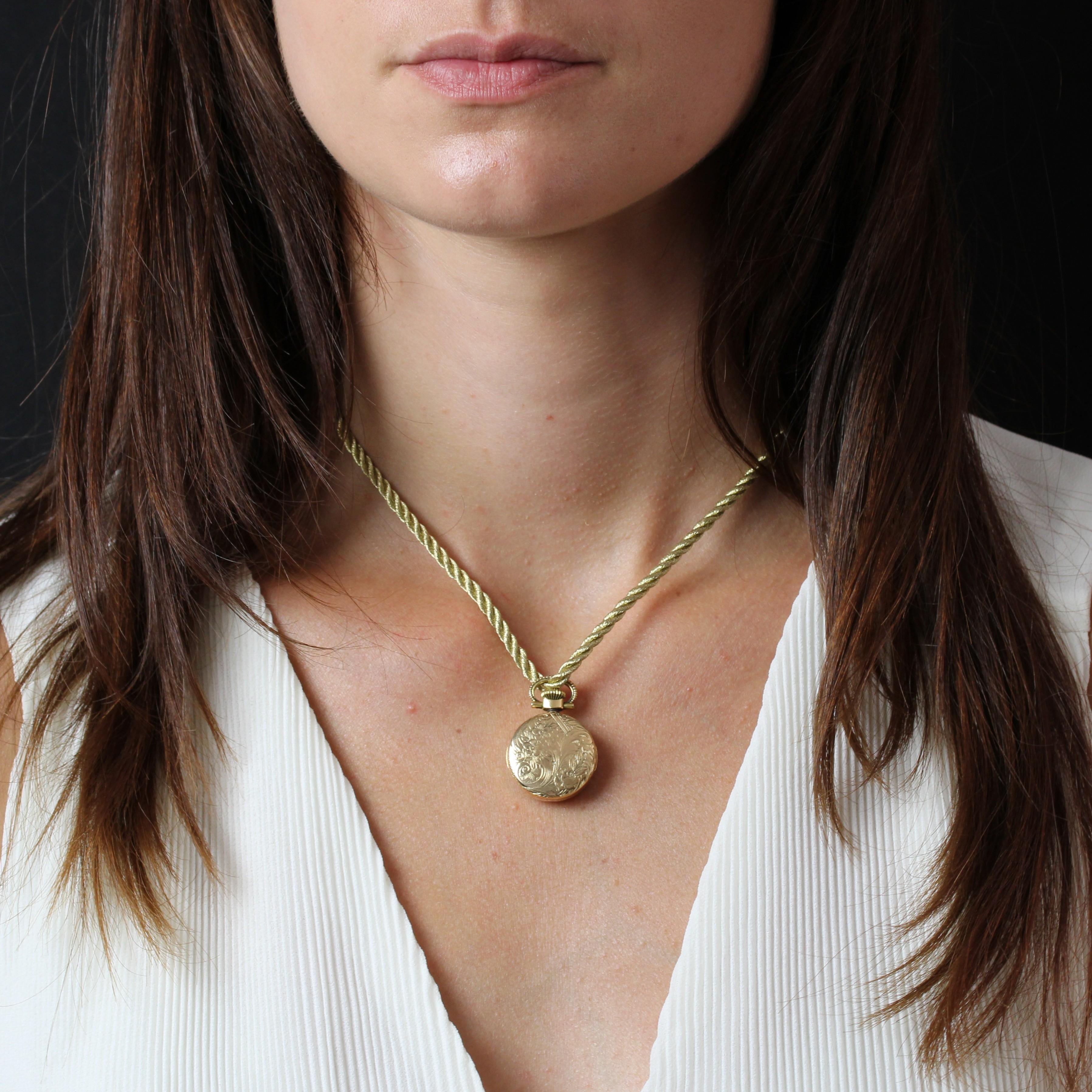 Montre-pendentif en or jaune 18 carats, poinçon tête d'aigle.
Montre de poche Vintage, le boîtier est rond et gravé de motifs végétaux sur tout le pourtour. Le fond est plaqué or, gravé et marqué Flamor, avec des aiguilles noires et des chiffres