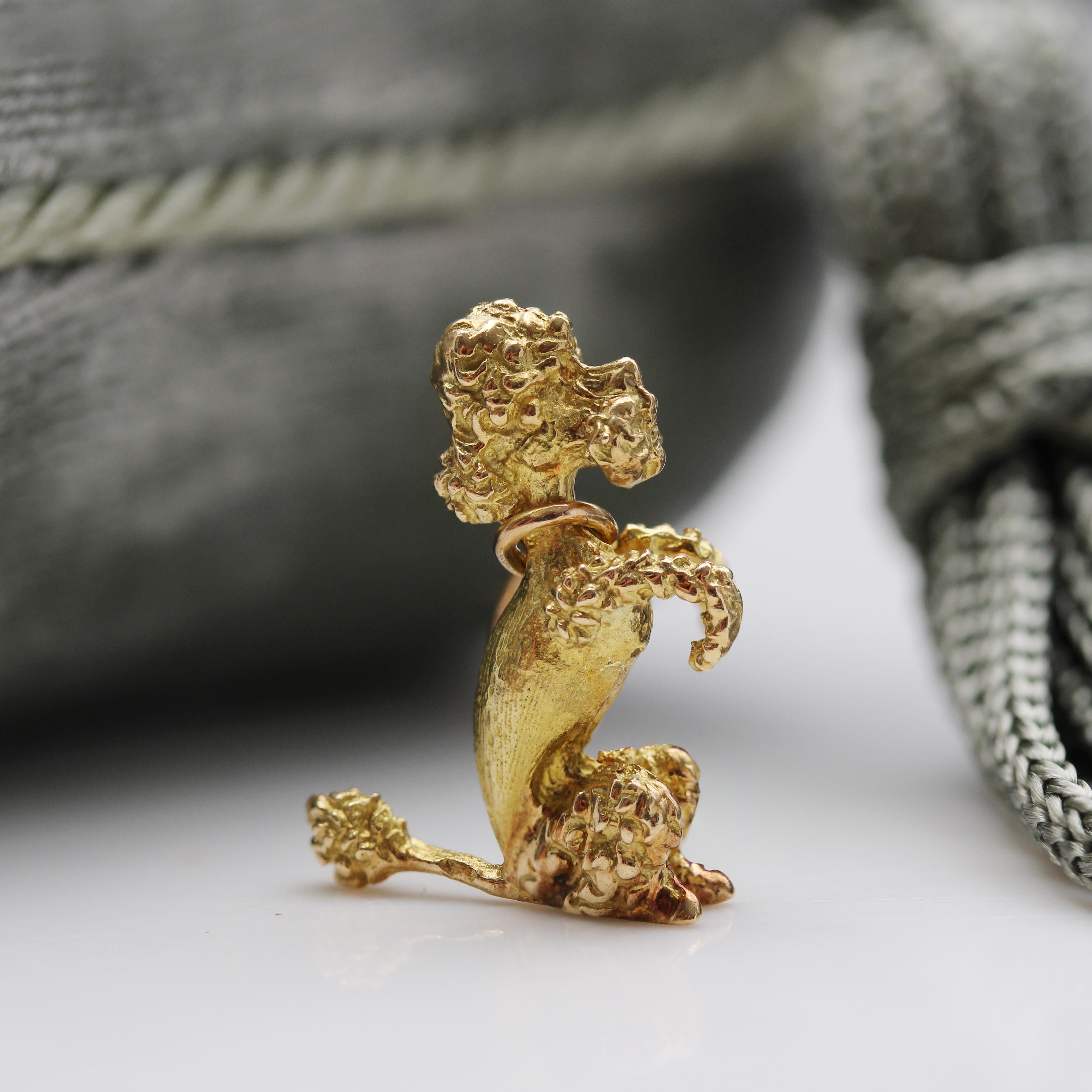 Pendant in 18 karat yellow gold, eagle head hallmark.
Crafted with great finesse and realism, this antique charm depicts a sitting poodle. The charm is held in place by a gold ring twisted around its neck.
Pendant sold alone, without its chain of