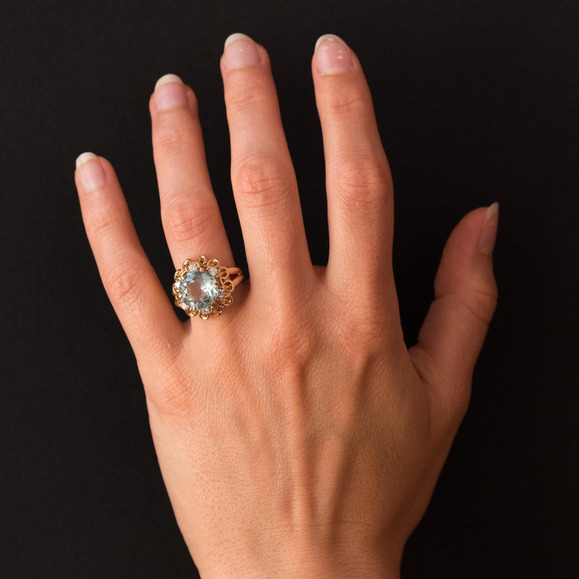 Ring in 18 karats rose gold, and platinum, dog's head hallmark.
A retro jewel, this ring is set with claws on top of a round aquamarine surrounded by 6 modern brilliant cut diamonds. The mounting is made of gold threads wrapped between them. The