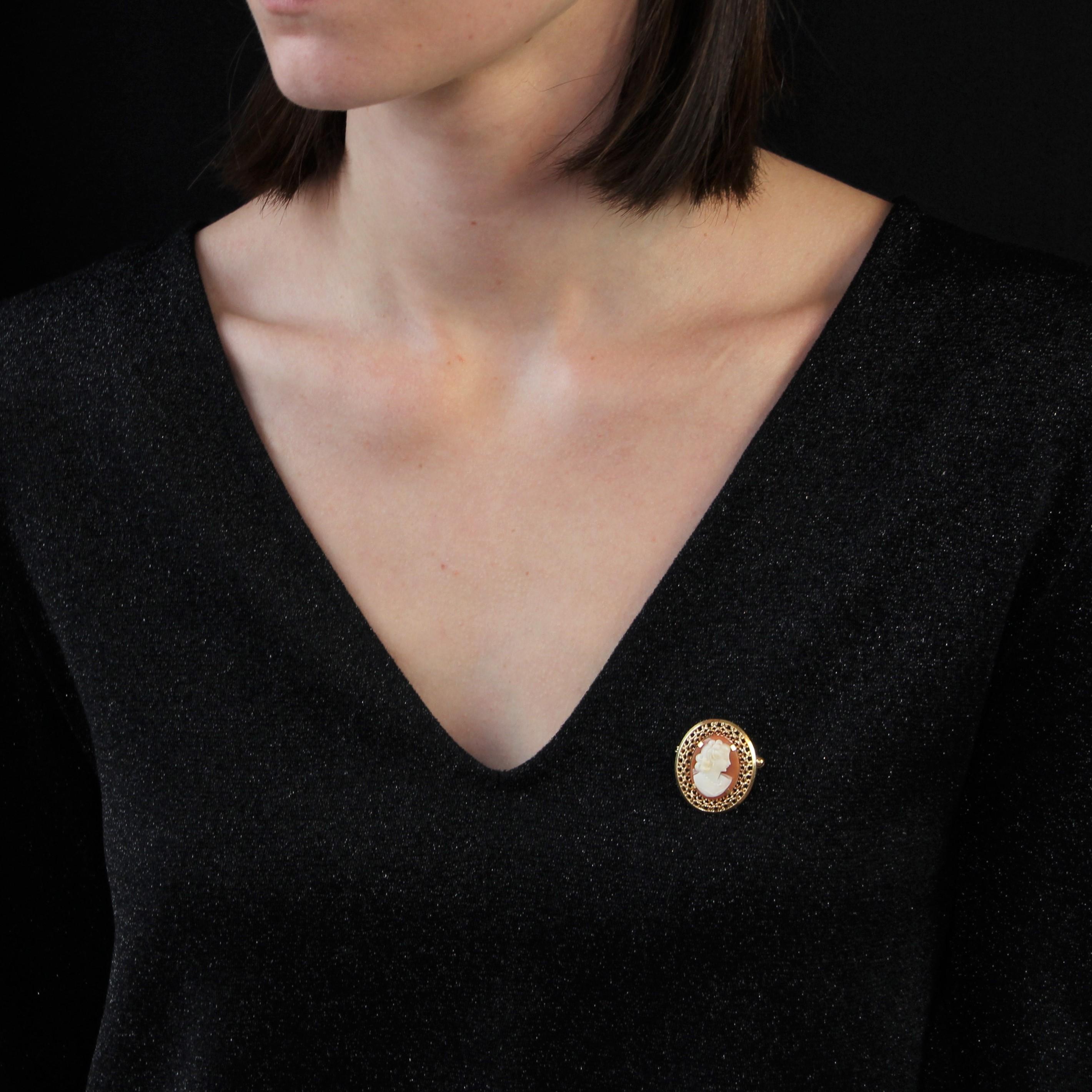 Brooch - pendant in 18 karat yellow gold, eagle head hallmark.
Of oval shape, this cameo on shell brooch represents a woman elegantly dressed. The surrounding of this brooch is decorated with gold polylobes and openwork. On the back is a clasp