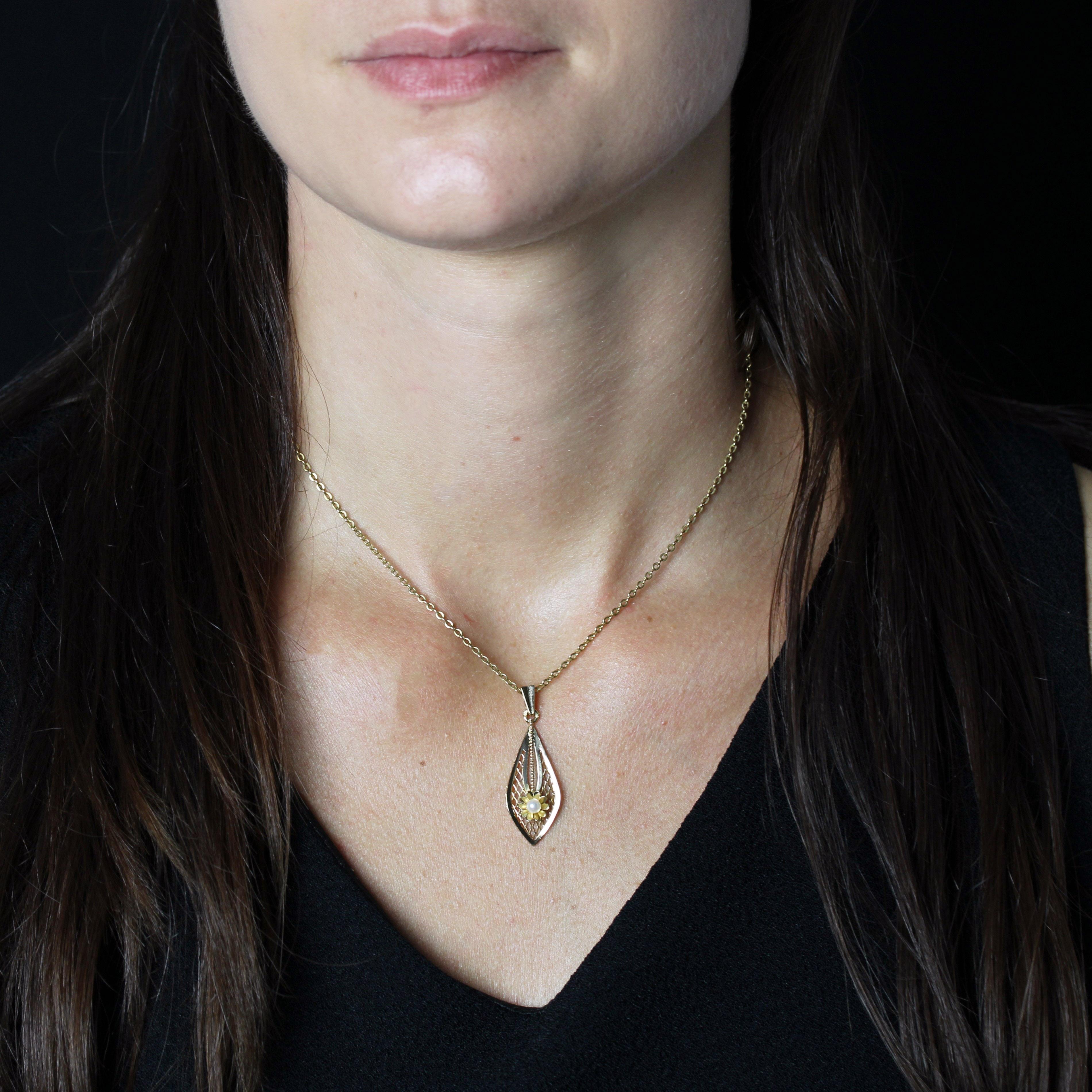 Ciondolo in oro giallo 18 carati, marchio di fabbrica con testa d'aquila.
Pendente in oro giallo leggermente concavo a forma di goccia, traforato con un motivo a reticolo in oro e decorato con un fiore applicato con una piccola perla coltivata, il