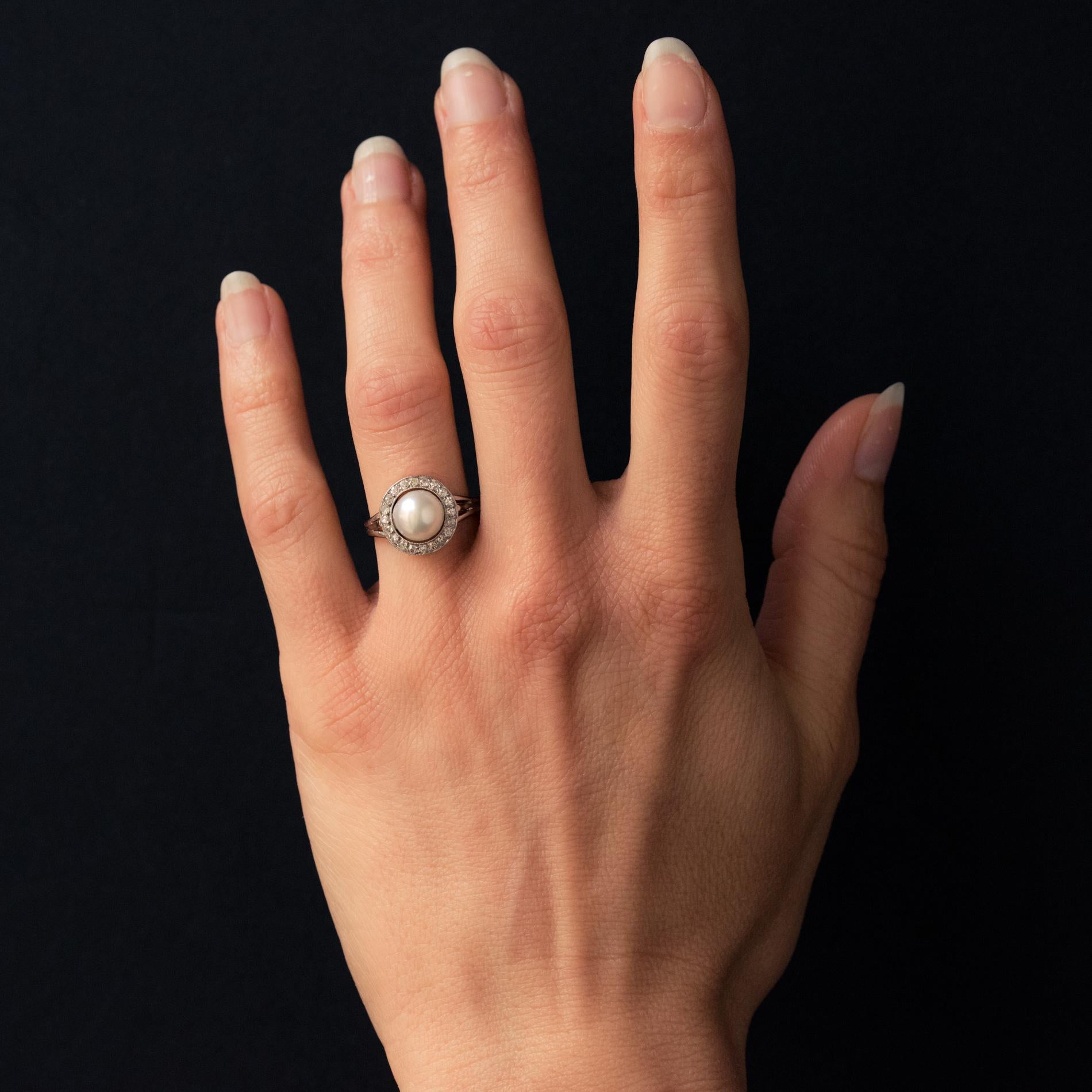 Ring in 18 karat white gold, eagle's head hallmark and platinum, dog's head hallmark.
Feminine antique ring, it is set, in a closed setting, in the center with a pearl white orient cultured pearl, in an entourage of diamonds. The ring of the