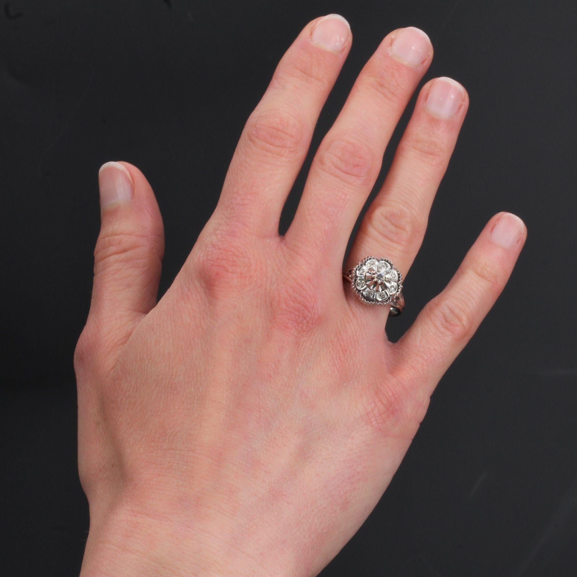 Ring aus 18 Karat Weißgold, Adlerkopfpunze.
Dieser Retro-Ring in runder, polygonaler und gekerbter Form ist auf der Spitze eines Diamanten im Brillantschliff gefasst, der von Diamanten im Rosenschliff umgeben ist.
Gewicht des Hauptdiamanten: ca.