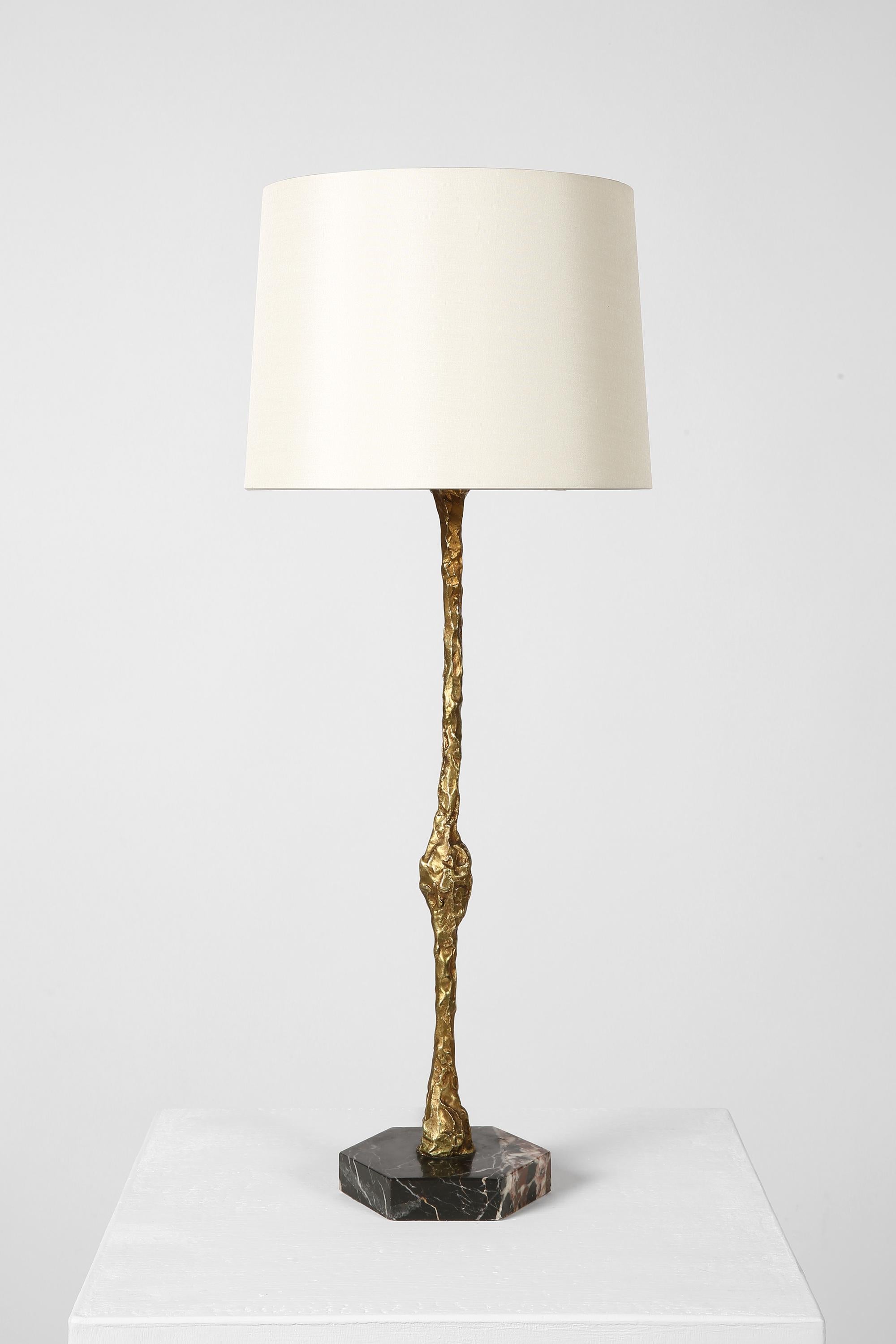 Lampe de table chic, de style Giacometti, avec une tige élancée en bronze moulé et une base hexagonale en marbre noir poli.

Livré avec un abat-jour en soie dupion blanc cassé.