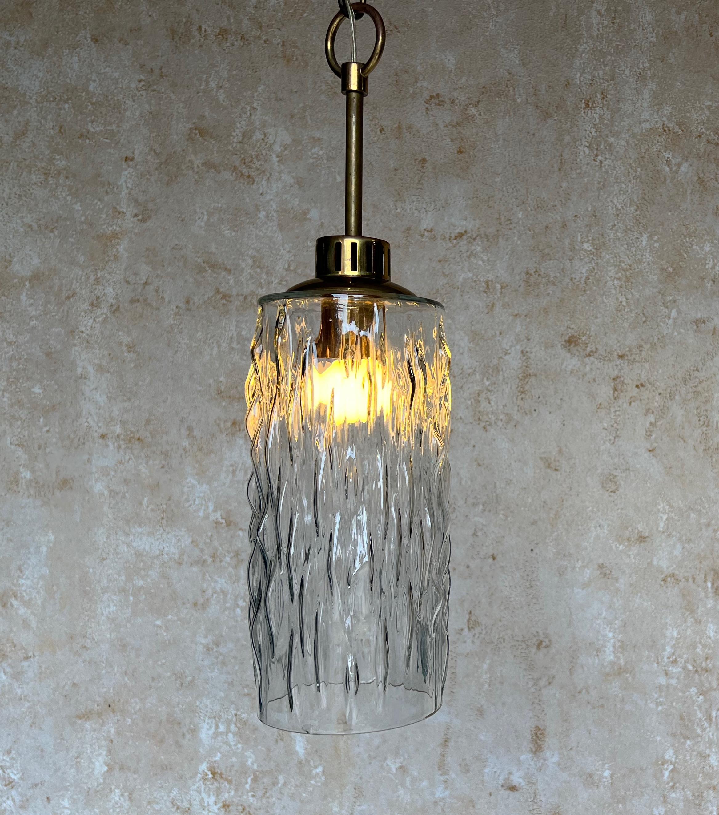 This hanging light fixture from 1960s France is a beautiful and unique piece of vintage lighting design. The textured glass attached to a brass stem gives it an elegant and sophisticated appearance that will elevate any space. Measuring 20.5 inches