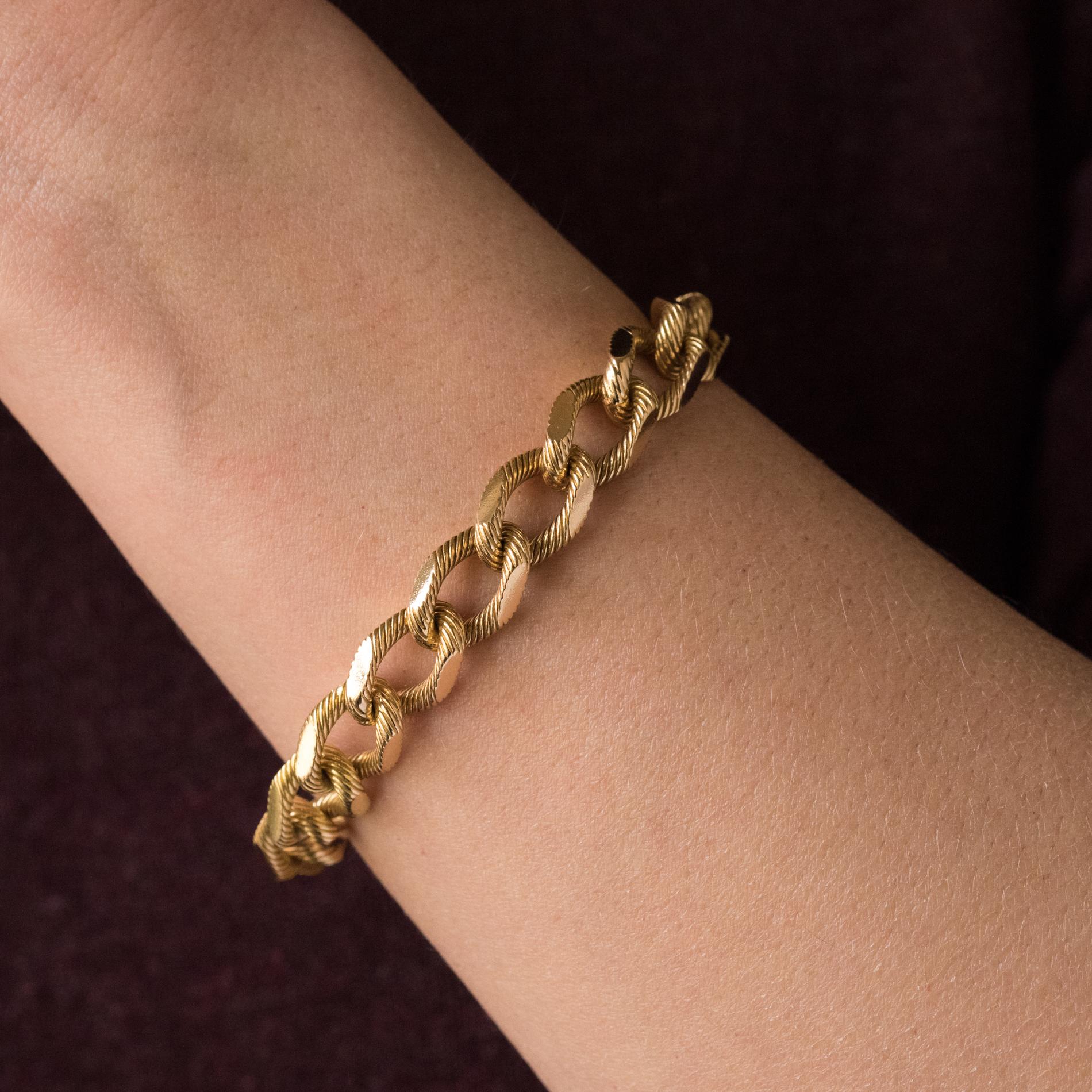 Bracelet in 18 karats yellow gold, rhinoceros hallmark.
Massive retro bracelet, it consists of a textured gourmette mesh. The clasp is a ratchet with a safety 