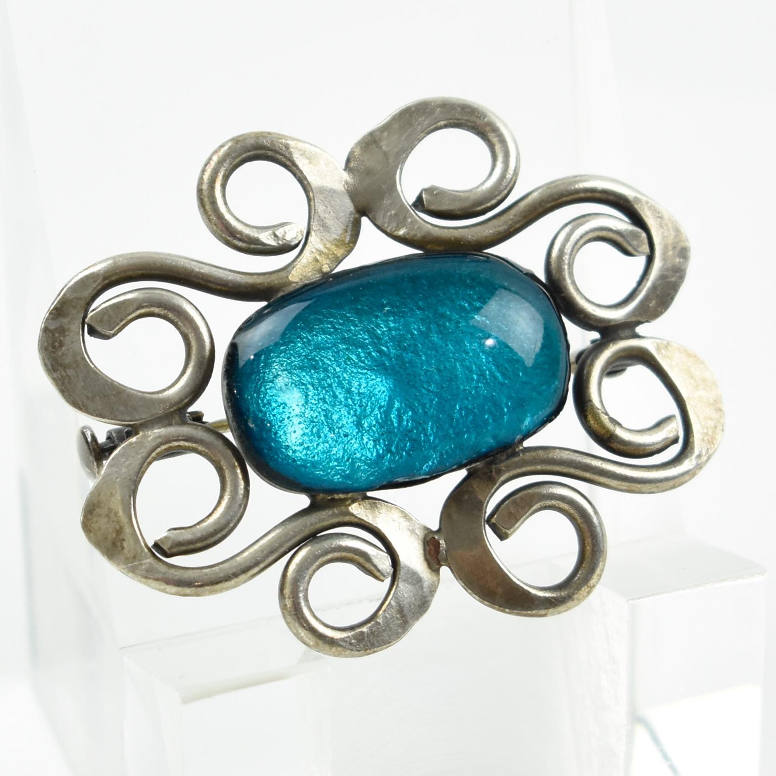 French Mid-Century Modern 1960s pin brooch. Geometric design with floral-inspired shape, reminiscent of Jacques Gautier's work. Silvered metal frame topped with electric blue enamel glass with a silver foil background. Security closing clasp. No