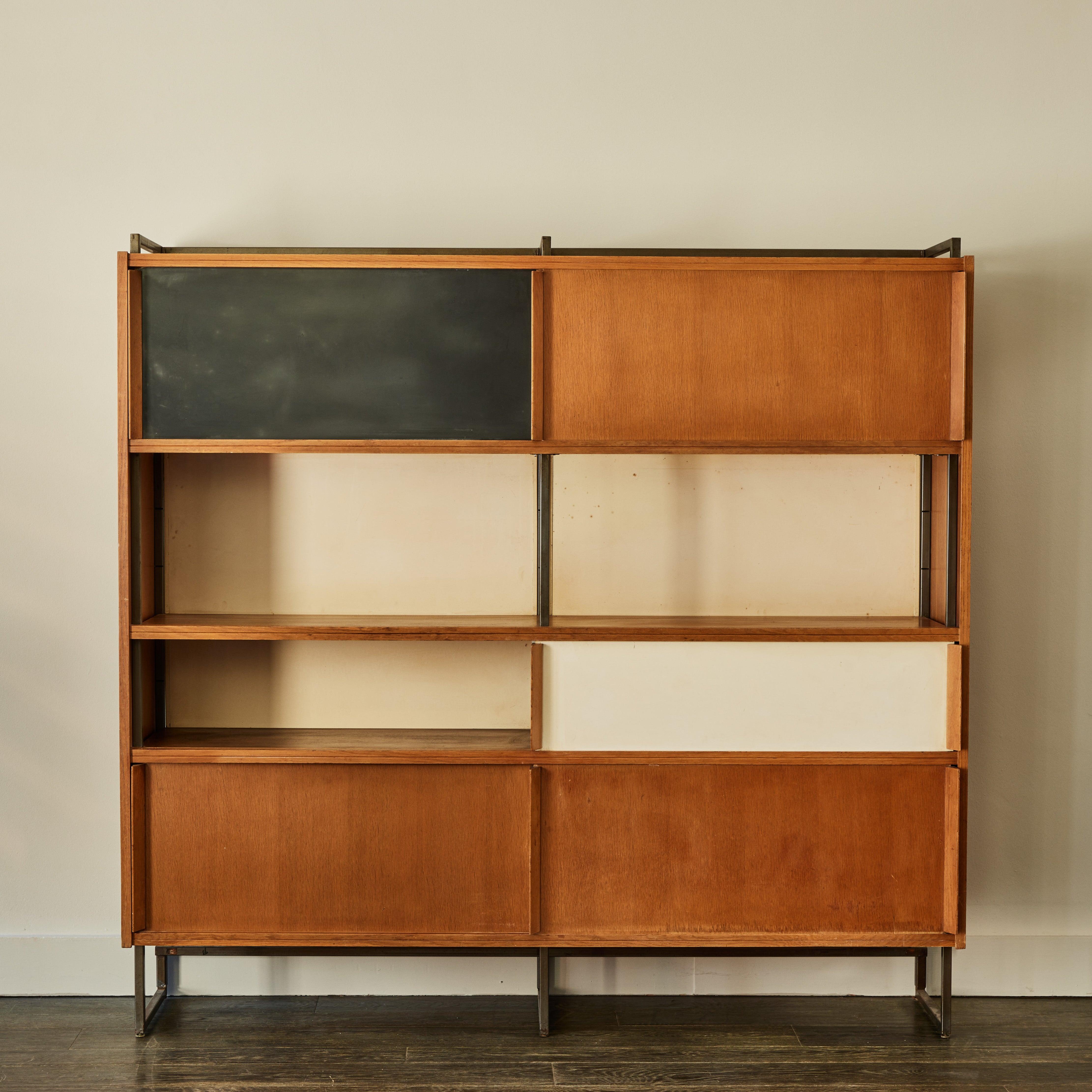 Charlotte Perriand style midcentury display cabinet or bookcase in walnut with three walnut sliding doors, one black door and one white door. Three compartments are open without doors.  Chic and with great versatility, the compartmental organization