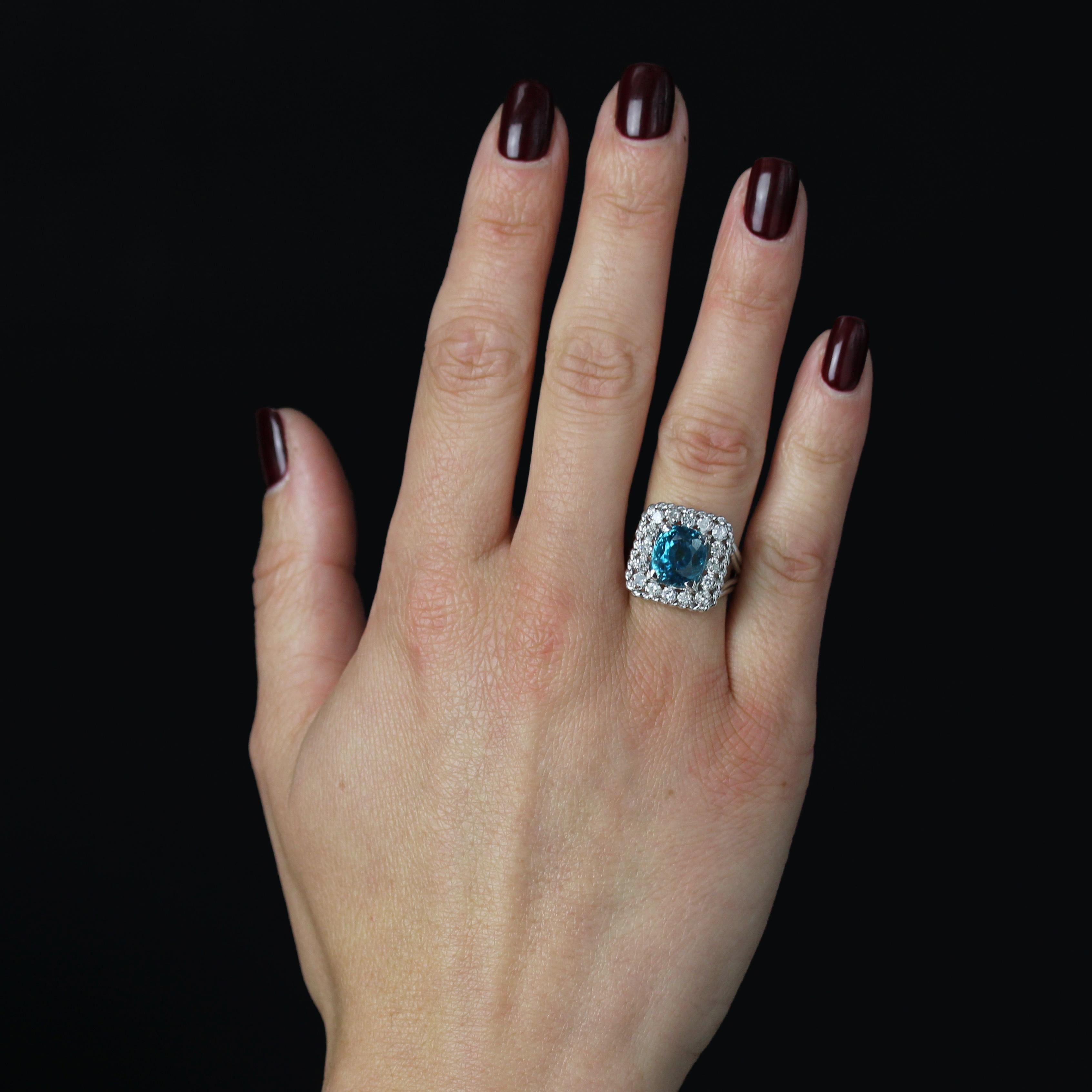 Ring in platinum, dog's head hallmark.
Magnificent antique ring, its rectangular setting is adorned with 8/8 cut diamonds held in place by claws. In the center, a large natural blue cushion-cut zircon is set. A platinum cord surrounds the entire