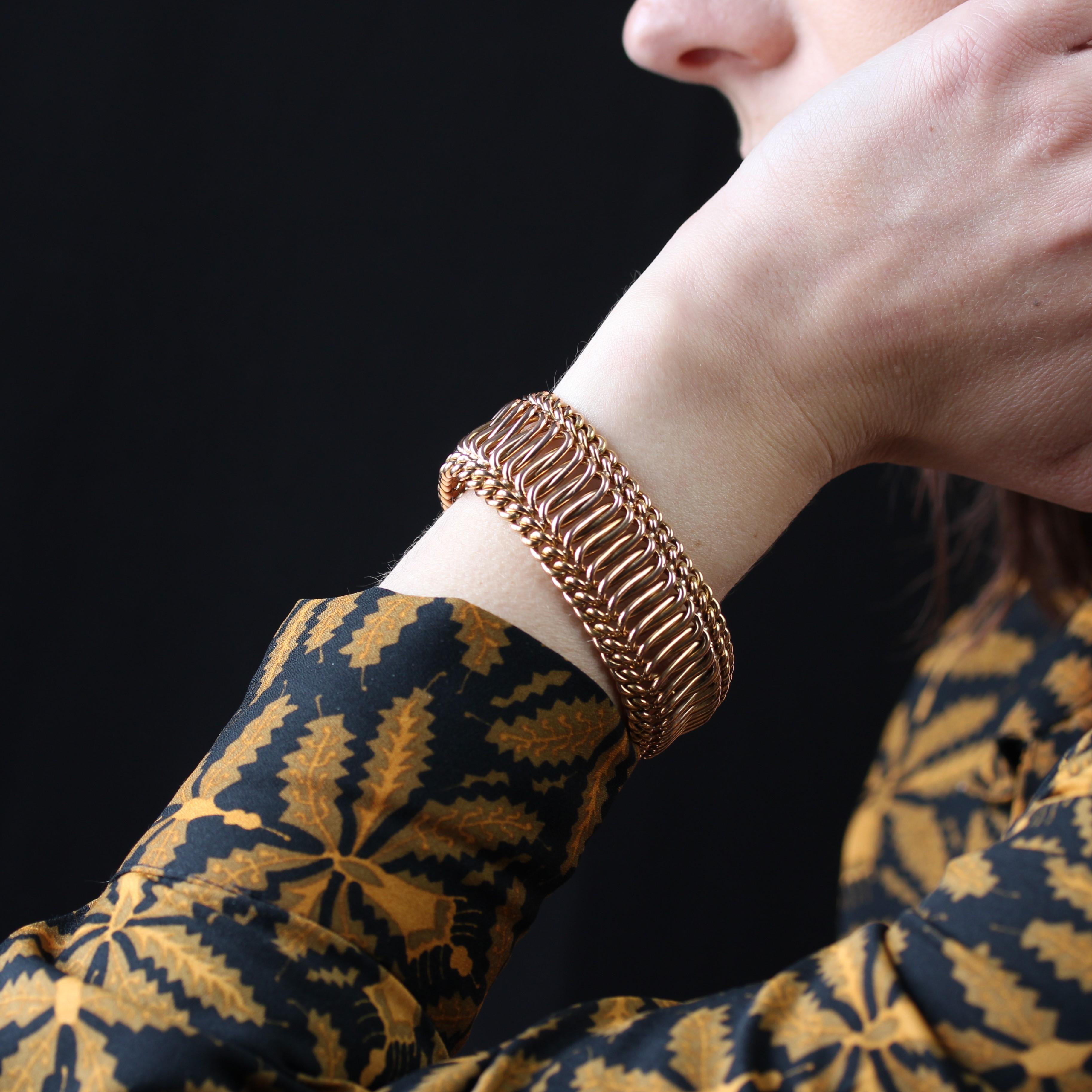 Bracelet in 18 karat rose gold, eagle head and rhinoceros head hallmarks.
A wide, antique bracelet, it is formed of a supple double gourmette mesh framing a mesh of large, intertwined oval rings. The clasp is a large ratchet with two 8 safety
