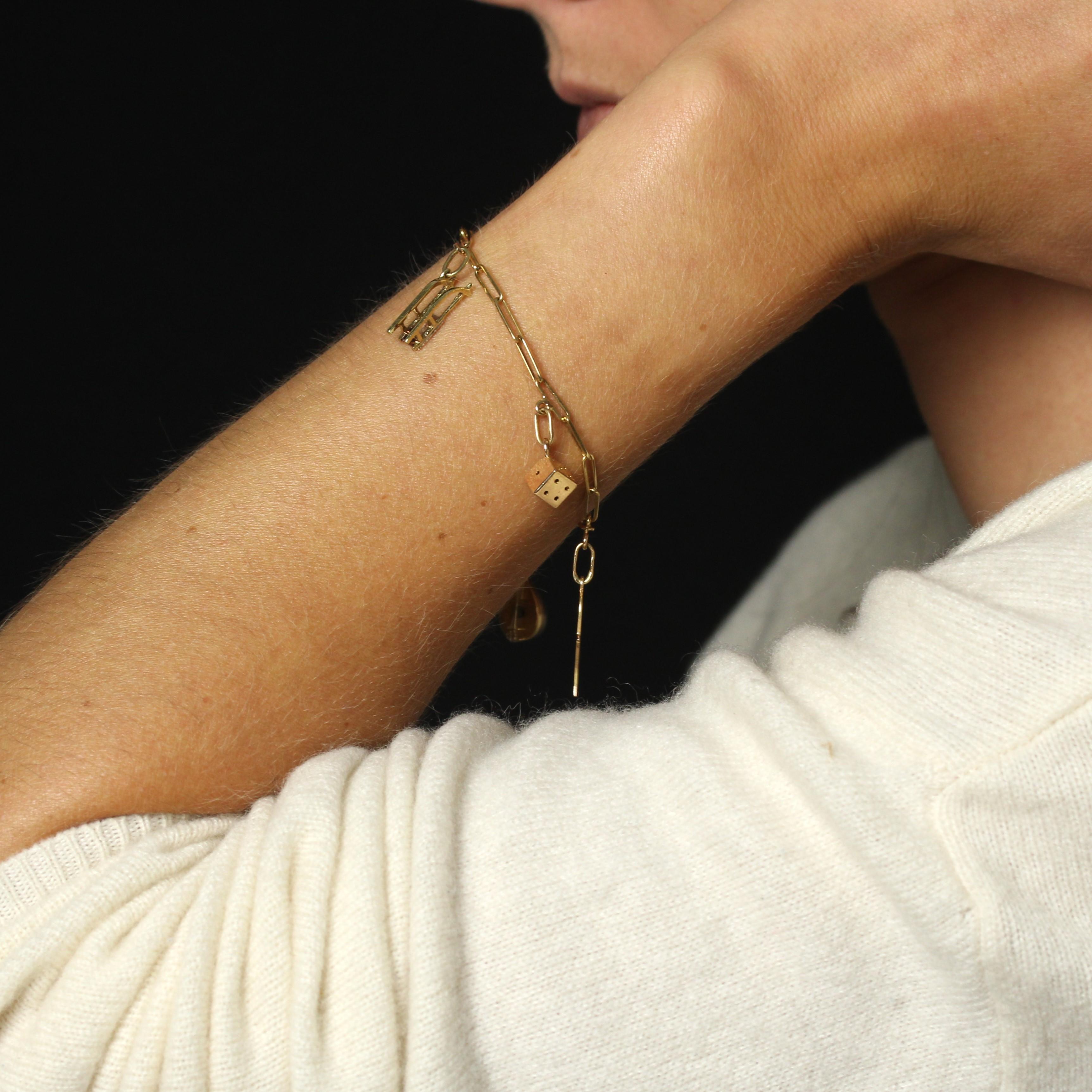 Bracelet in 18 karat yellow gold, eagle head hallmark. 
A delightful and original bracelet, it features a figaro link fastened with a spring ring. 5 charms, also in yellow gold, are attached by small gold rings and represent an antique sledge, a