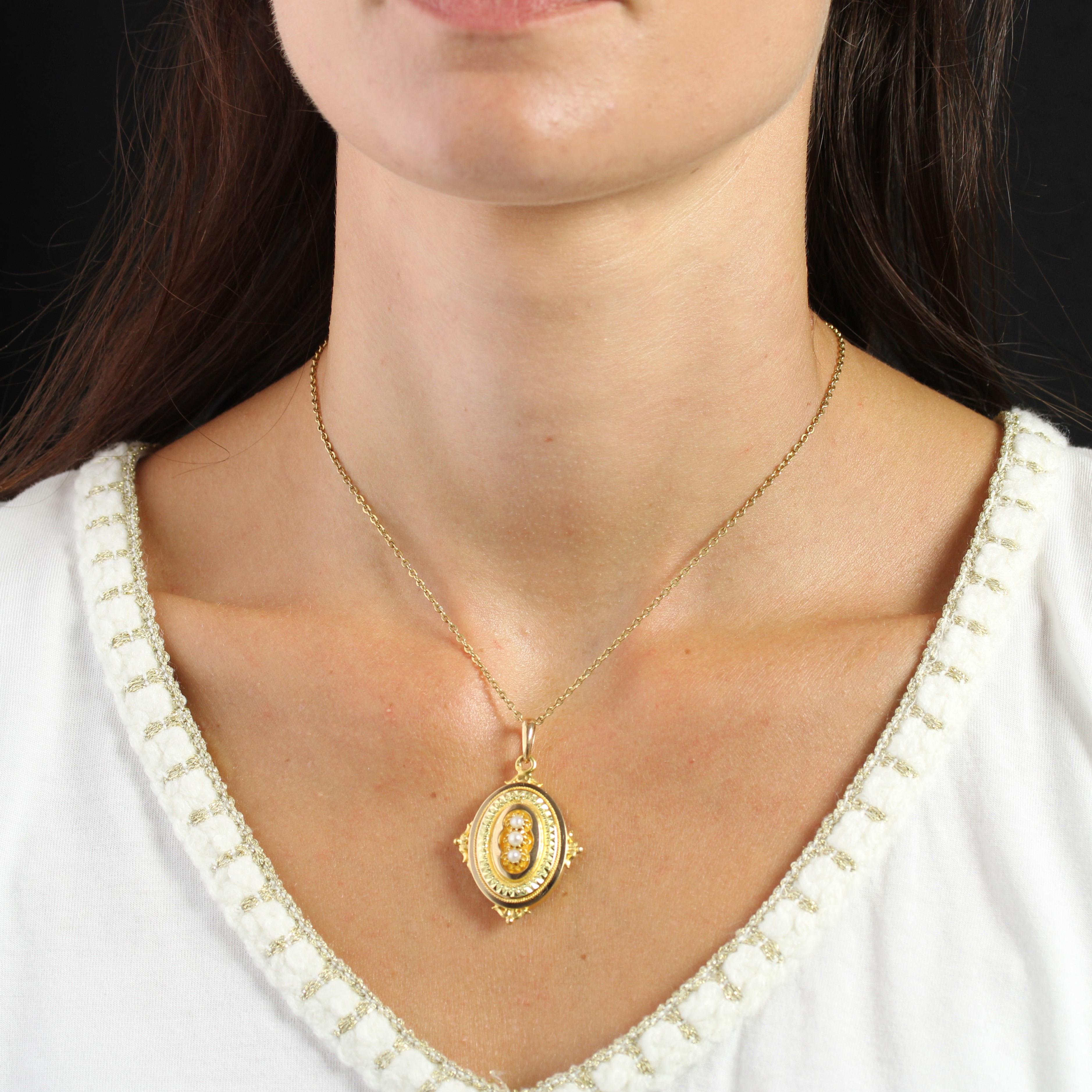 Anhänger aus 18 Karat Gelbgold, Adlerkopfpunze.
Das ovale Medaillon ist mit 3 halben Zuchtperlen in einem facettierten und ziselierten Rahmen geschmückt. Eine goldene Kordel umrandet das Ganze. In den 4 Himmelsrichtungen schmücken Arabeskenmotive