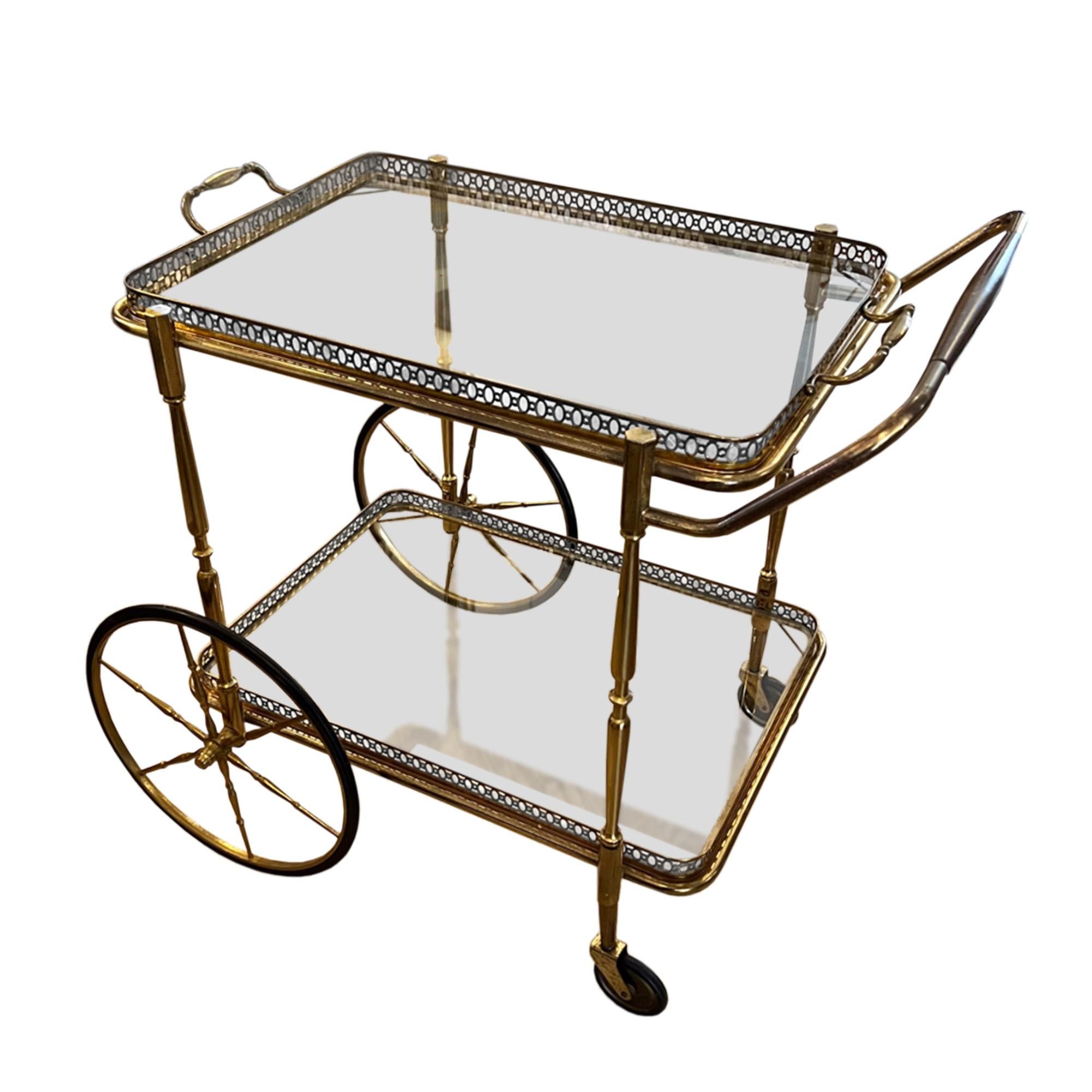 This delightful small drinks trolley was made in France in the 1960s.

Decorative brass frame with detailed, pierced galleries on both shelves. The top tray lifts off with brass handles to be used separately and the wheels work perfectly too. 

You