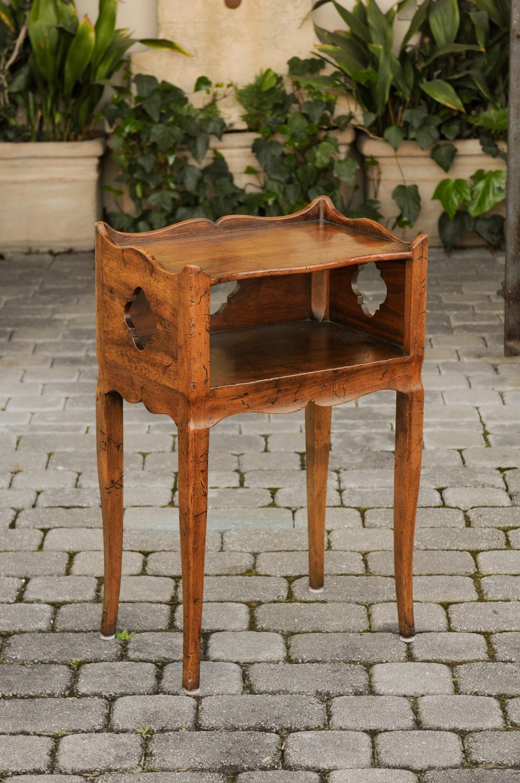 A French walnut nightstand table from the mid-20th century, with open shelf, quatrefoil motifs and curving legs. Born in France during the midcentury period, this charming side table features a rectangular top surrounded by a three-quarter gallery,