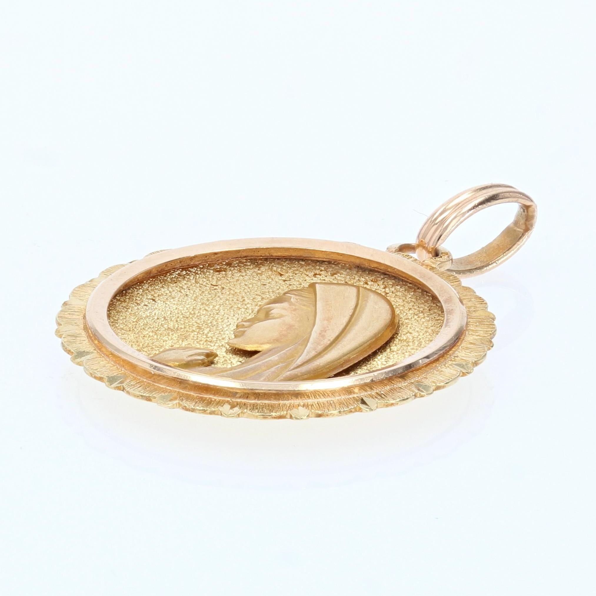Medal in 18 karat yellow gold, eagle head hallmark.
Religious pendant concave on the front and convex on the back, it represents the profile of the Virgin Mary praying. The bottom of the medal is in yellow gold, encircled with rose gold and bordered