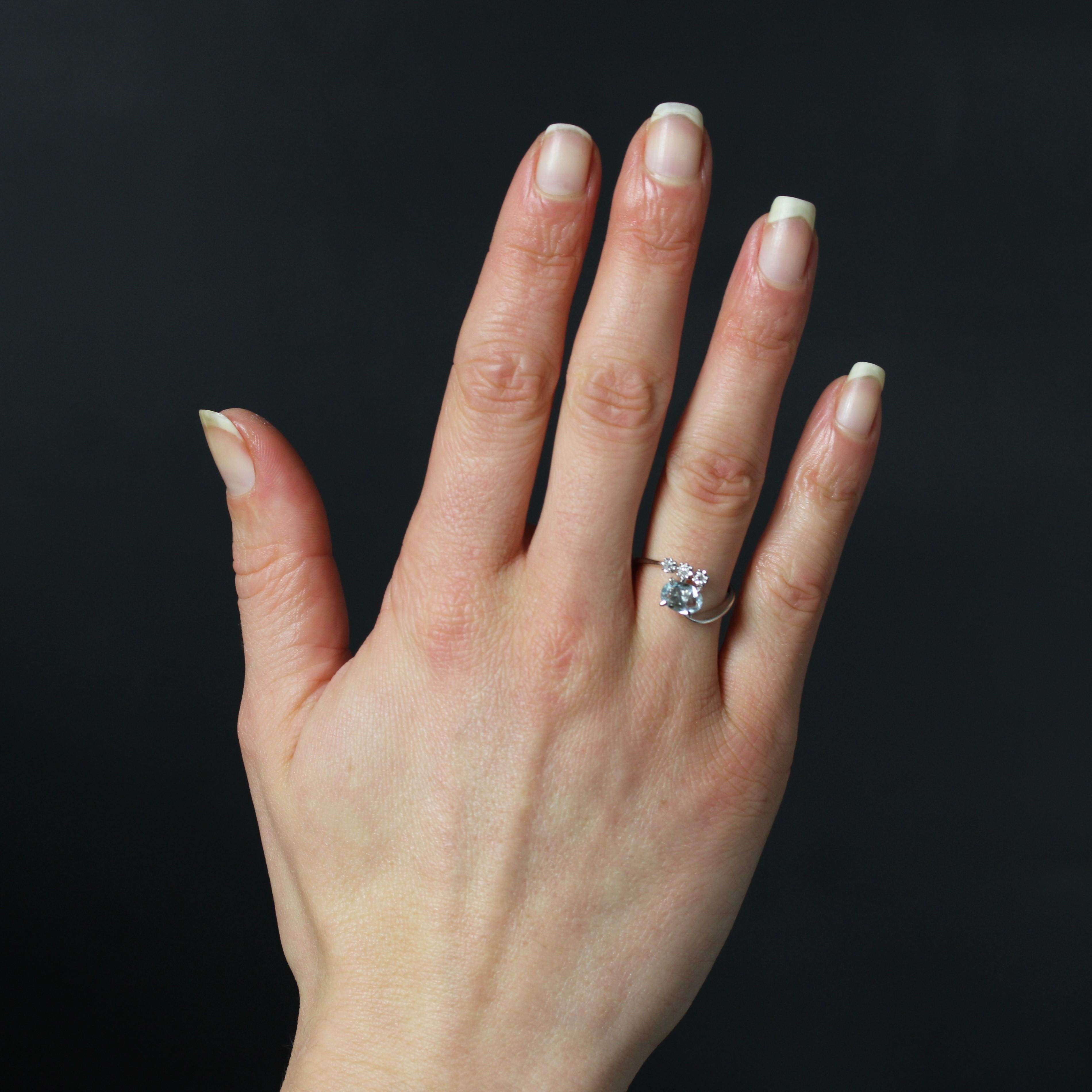 Ring in 18 karat white gold, eagle head hallmark.
This vintage ring features an asymmetrical flat band that holds an oval aquamarine set with four claws at the top. Three star settings complete the decor, each adorned with a brilliant-cut