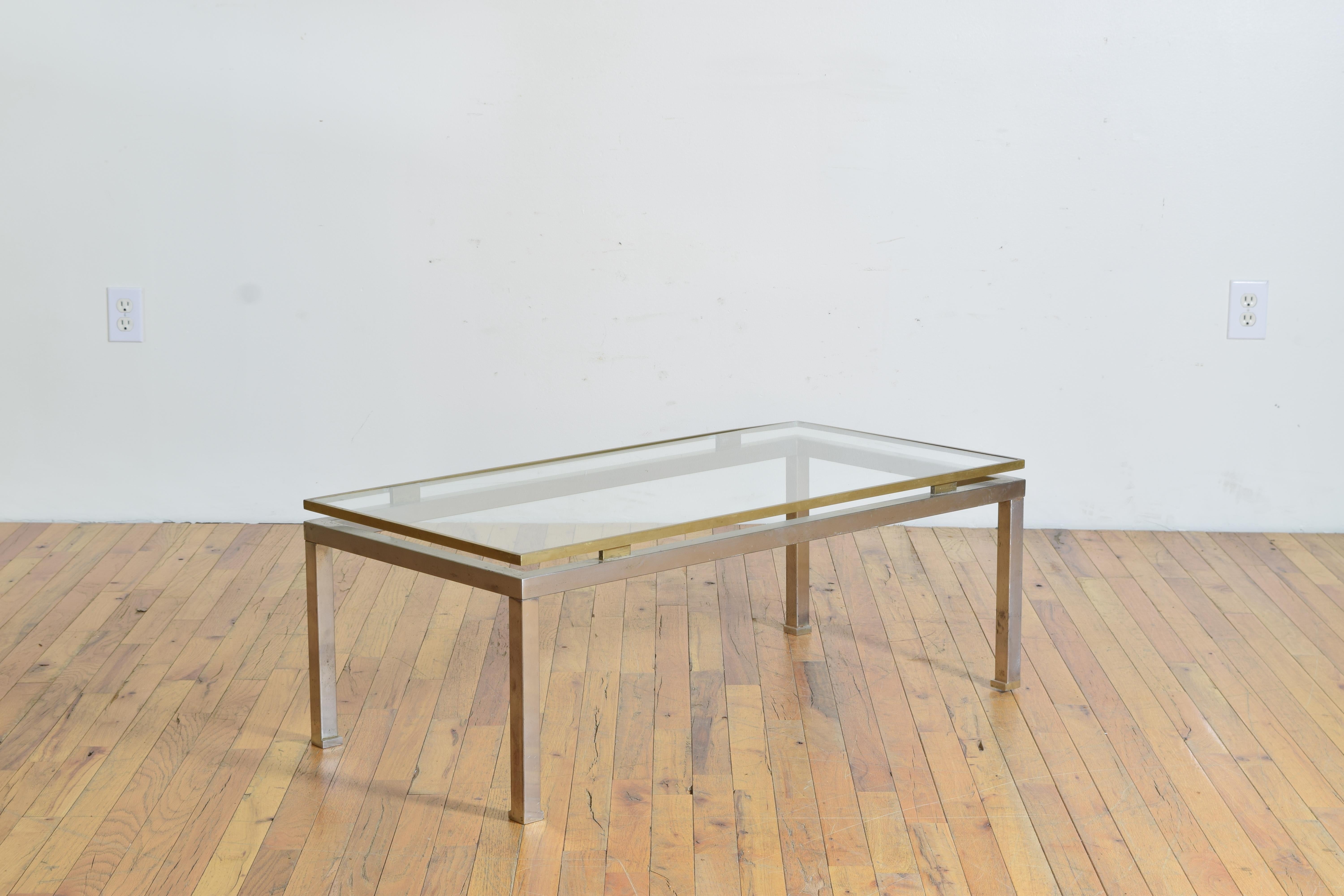 In the style of Romeo Rega, having a rectangular glass top within a brass frame “hovering” above a steel lower frame with straight legs and slightly notched feet