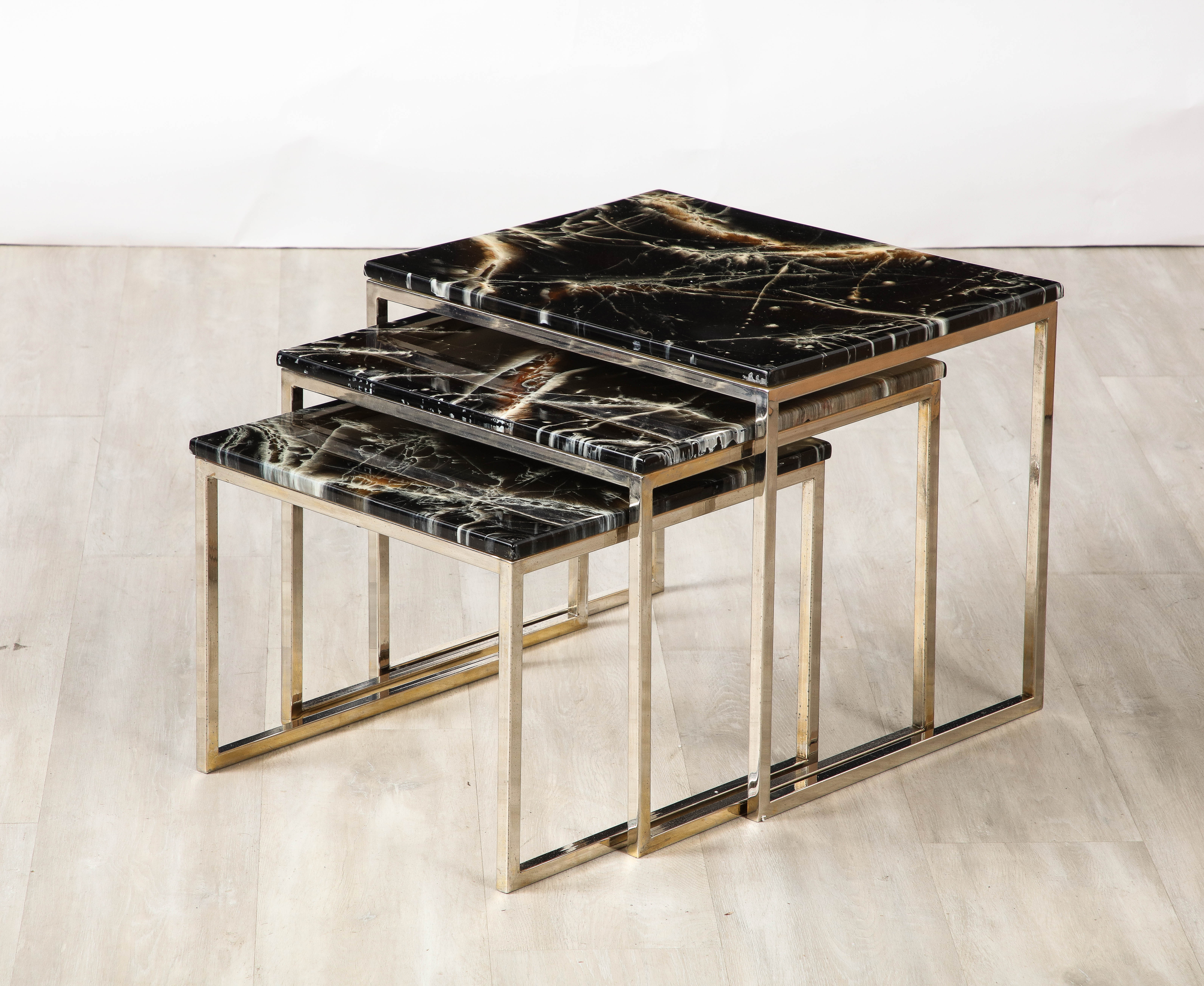 French 1970's nesting tables; consisting of three tables of varying heights, the tops in a laminate finish meant to simulate black banded agate; set into chrome supporting bases.  Highly versatile and very chic, indicative of the glamourous era of