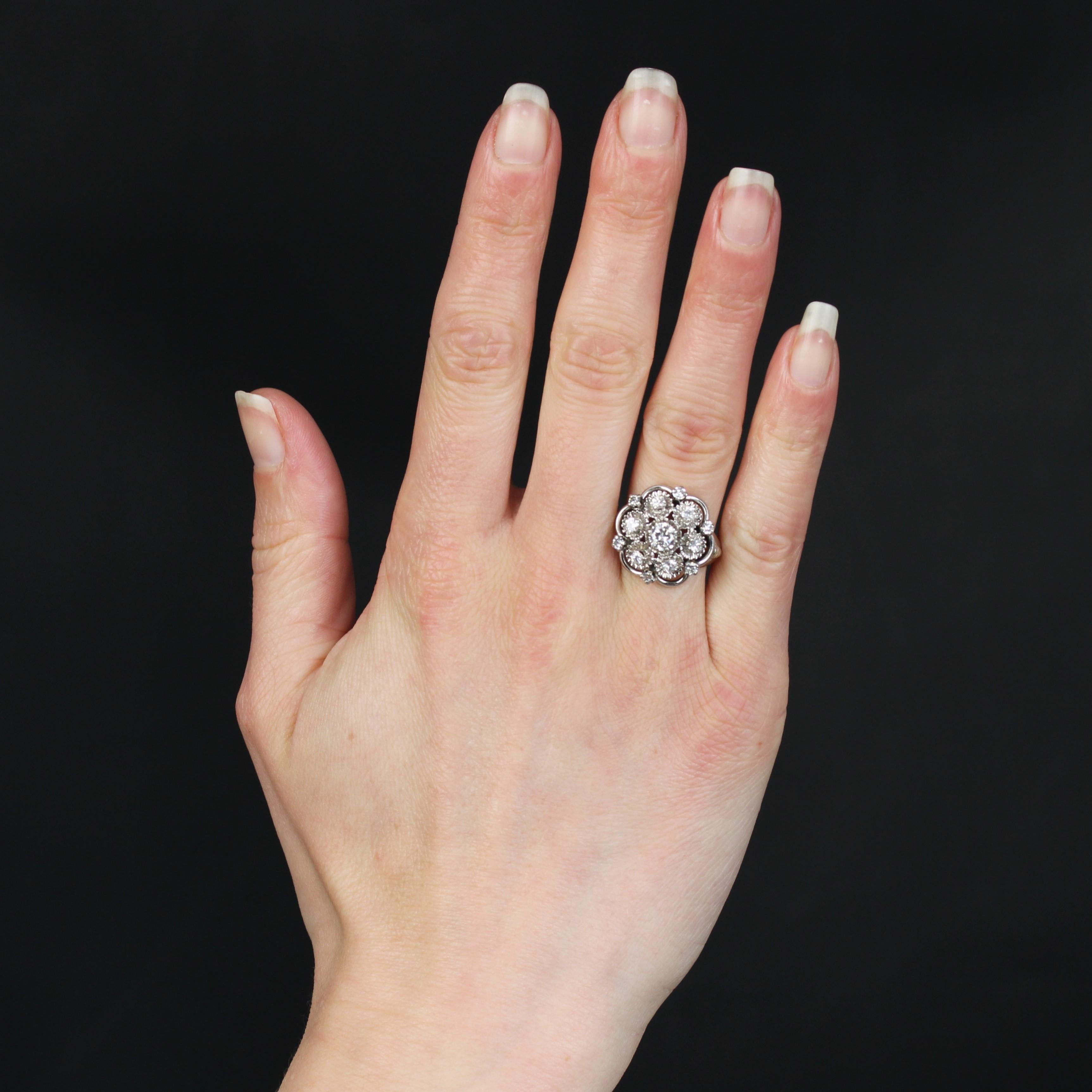 Ring aus 18 Karat Weißgold, Adlerkopfpunze.
Dieser voluminöse Blumenring ist mit Diamanten im modernen Schliff in verschiedenen Größen besetzt. Der größere zentrale Diamant ist in einer Illusionsfassung gefasst. Die umlaufenden Diamanten sind auf