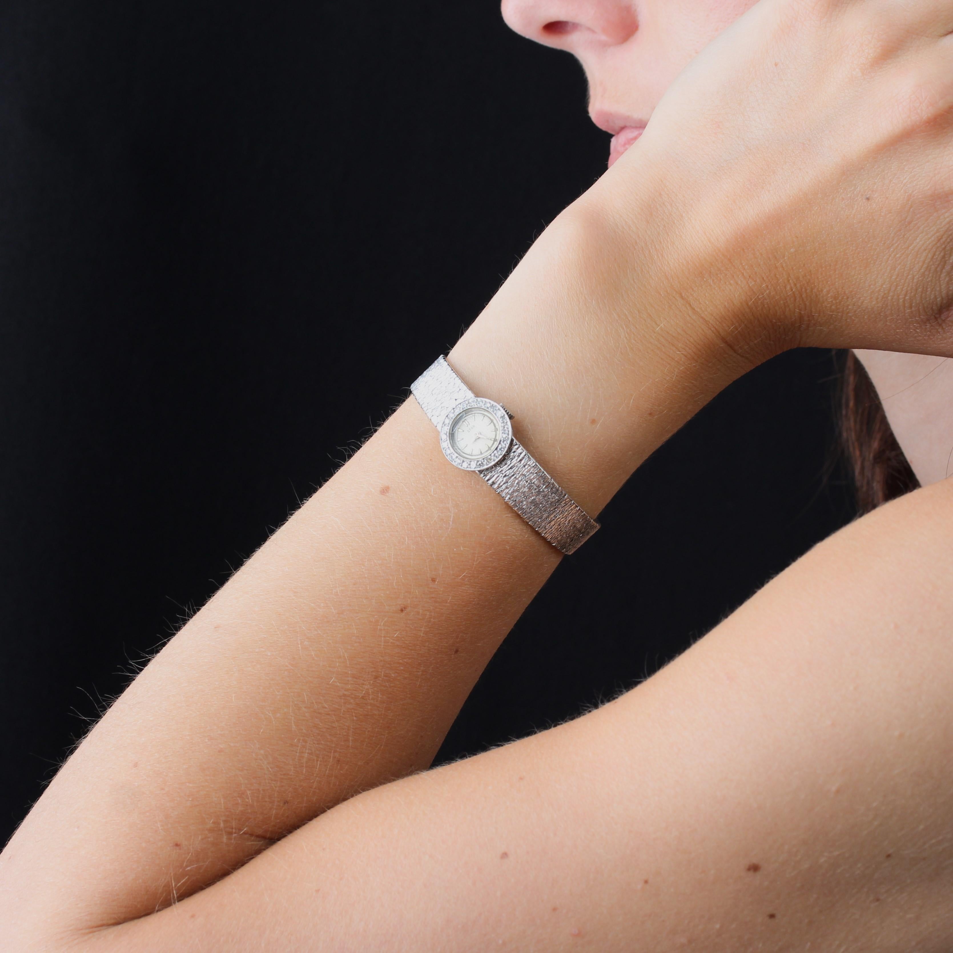 Watch in 18 karat white gold, eagle head hallmark.
The case of this vintage ladies' watch is round and surrounded by 8/8-cut diamonds. The back is light grey, and marked Star. The white gold bracelet is chased along its entire length, giving a