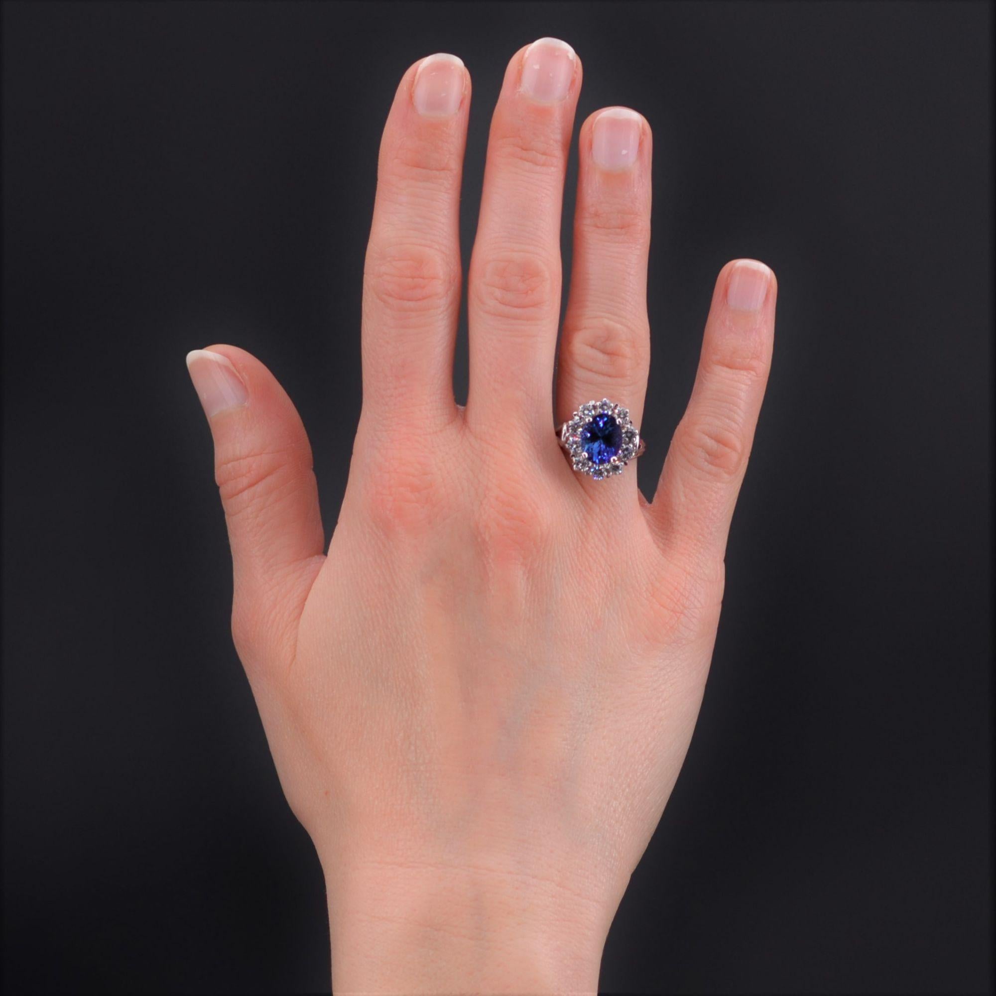Ring in 18 karat white gold, eagle head hallmark.
Magnificent retro ring, its setting is formed of gold threads that support a basket set in the center of an oval tanzanite, in a surround of modern brilliant- cut diamonds. On both sides, the ring is