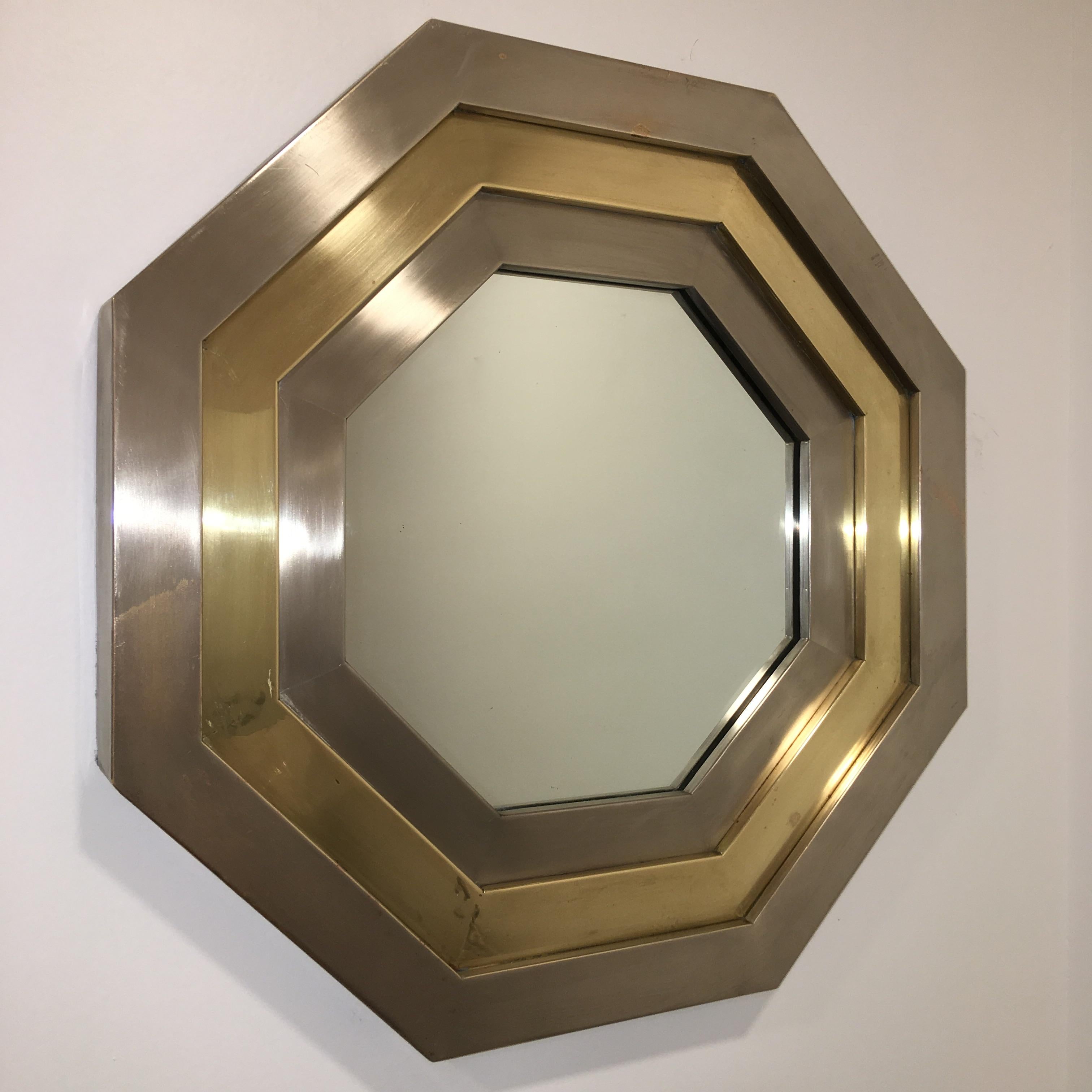 Look closely because if ever there was a sleeper it is this stunningly chic 1970's octagonal wall mirror framed with three bench worked bands of sheet brushed stainless steel and and sheet brass, skillfully cut, bent, hand shaped and joined with