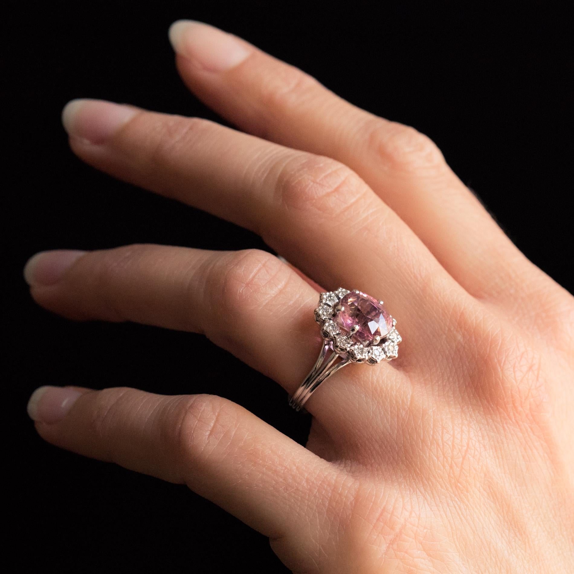 Ring in 18 karat white gold, eagle's head hallmark.
Lovely retro ring in white gold, it is adorned with a pink tourmaline set with 6 claws, surrounded by 8/8 size diamonds set in flower settings. The mounting is openwork and the ring formed of 3