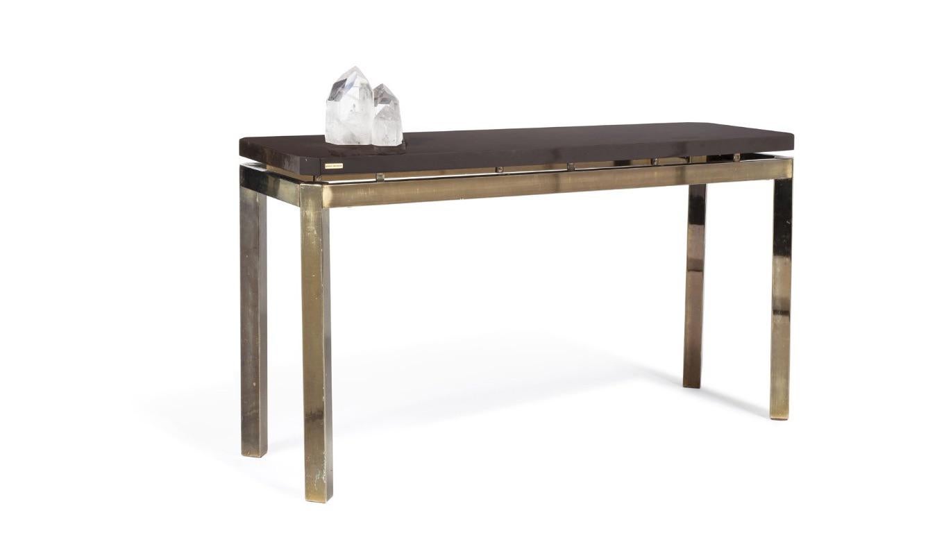 French (1970s) postwar design console table with a gilt brass base supporting a brown lacquered top having a protruding quartz sculpture (signed: Paco Rabanne on top edge).


There is nothing traditional about Paco Rabanne. Even his ascent into