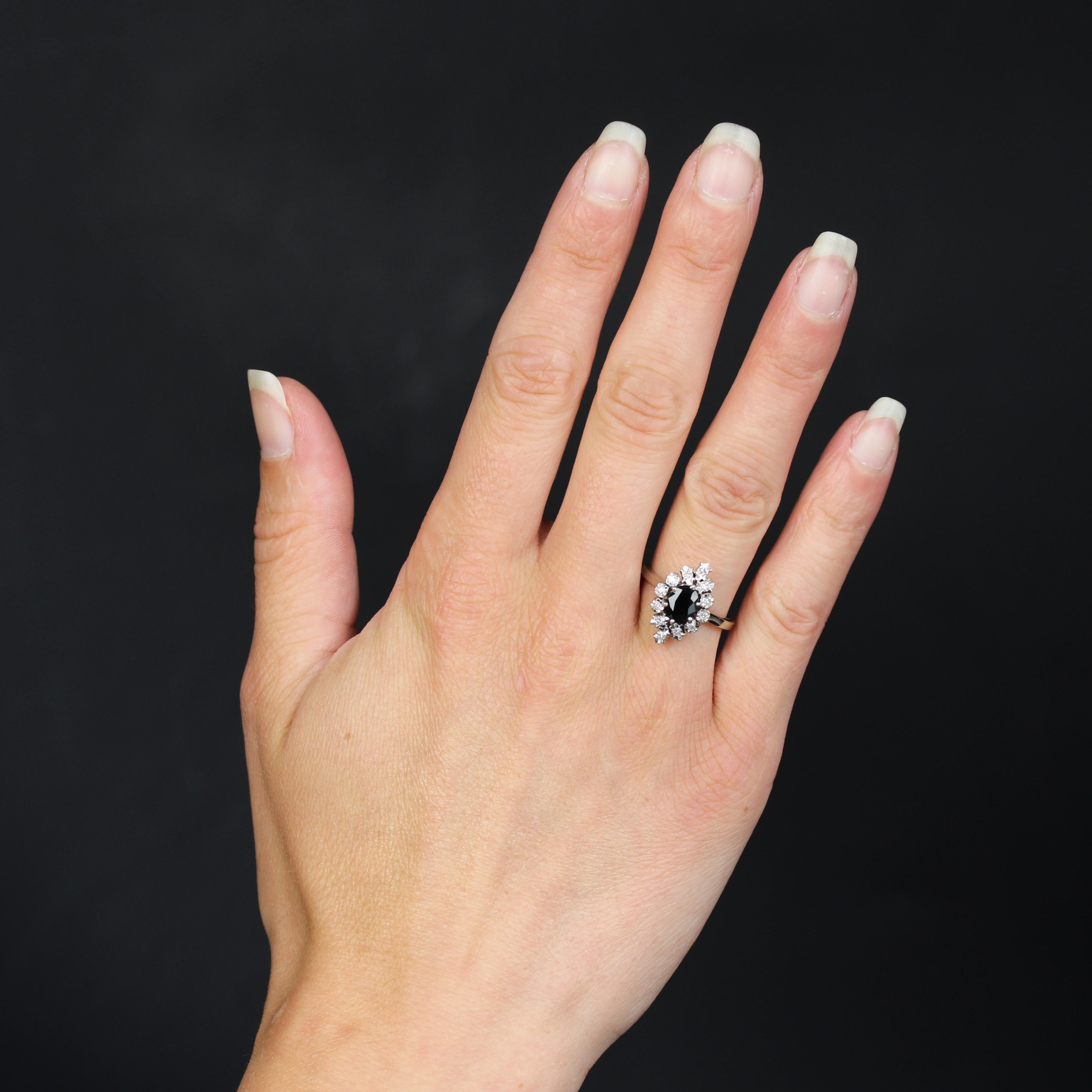 Anello in oro bianco 18 carati, marchio di fabbrica con testa d'aquila.
In ottime condizioni, questo anello vintage in oro bianco presenta uno zaffiro blu intenso al centro. Il contorno è composto da motivi geometrici cesellati, ognuno dei quali
