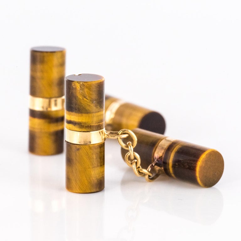 Pair of cufflinks in 18 karat yellow gold, eagle's head hallmark.
Each antique cufflink is set with two long tiger eye cylinders connected by a flexible chain.
Height : 6.8 mm, width : approximately 20mm, thickness : 7 mm, carabiner length : 15