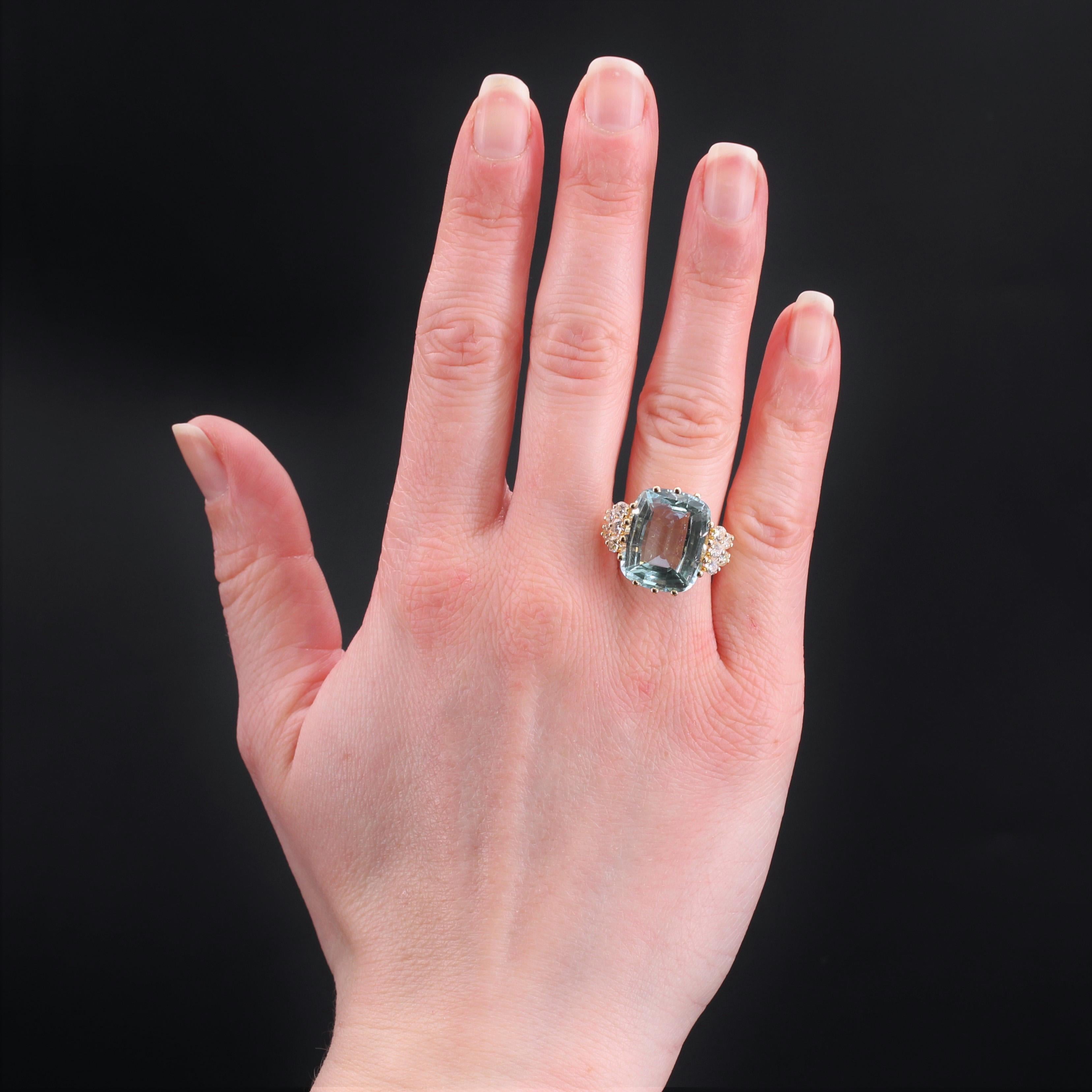 Ring aus 18 Karat Gelbgold, Adlerkopfpunze.
Ein Cocktailring par excellence: Dieser Retro-Ring trägt einen großen Aquamarin im Kissenschliff mit 2 x 5 modernen Diamanten im Brillantschliff auf beiden Seiten des Rings. Das Körbchen ist aus Golddraht