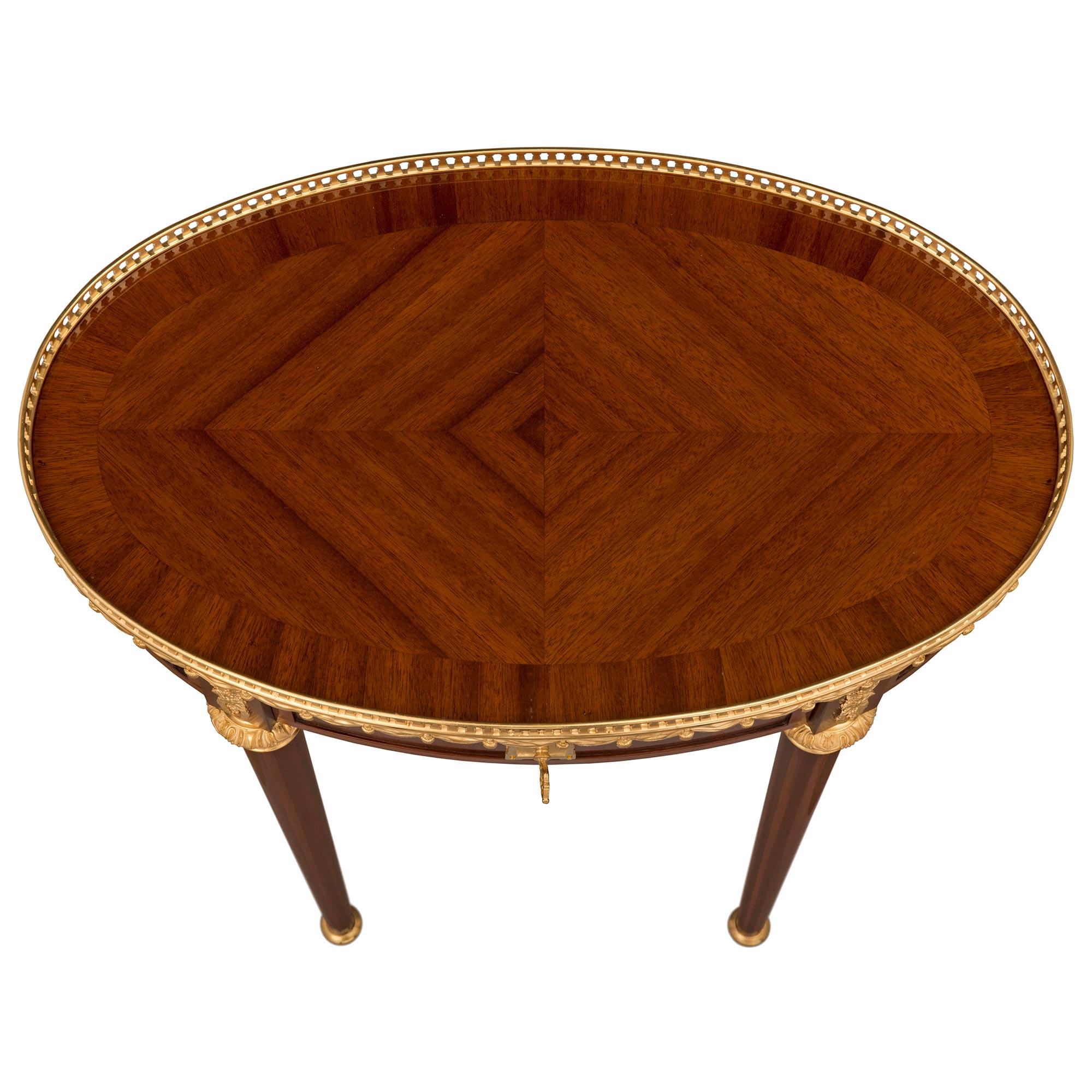 An elegant and very high quality French 19h century Louis XVI st. Belle Époque period Mahogany and ormolu side table signed by Maison Krieger. The oblong shaped one drawer table is raised by slender circular tapered legs with fine topie shaped ball