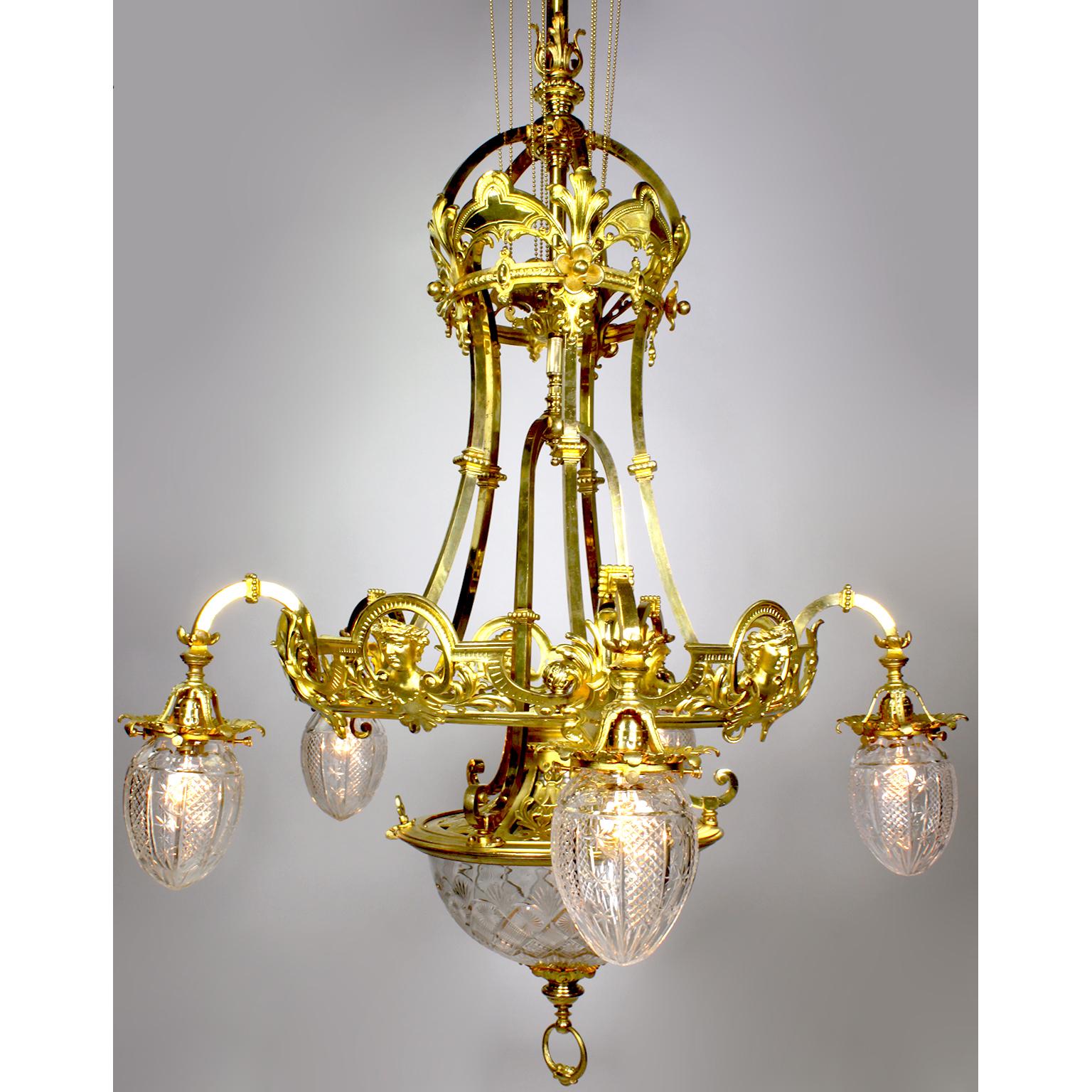 A fine and large French 19th-20th century Belle Époque gilt-bronze and cut-glass six-light figural chandelier. The elongated gilt-bronze body with a pierced apron and silvered lining with a beaded brass chain suspension around pulleys, decorated