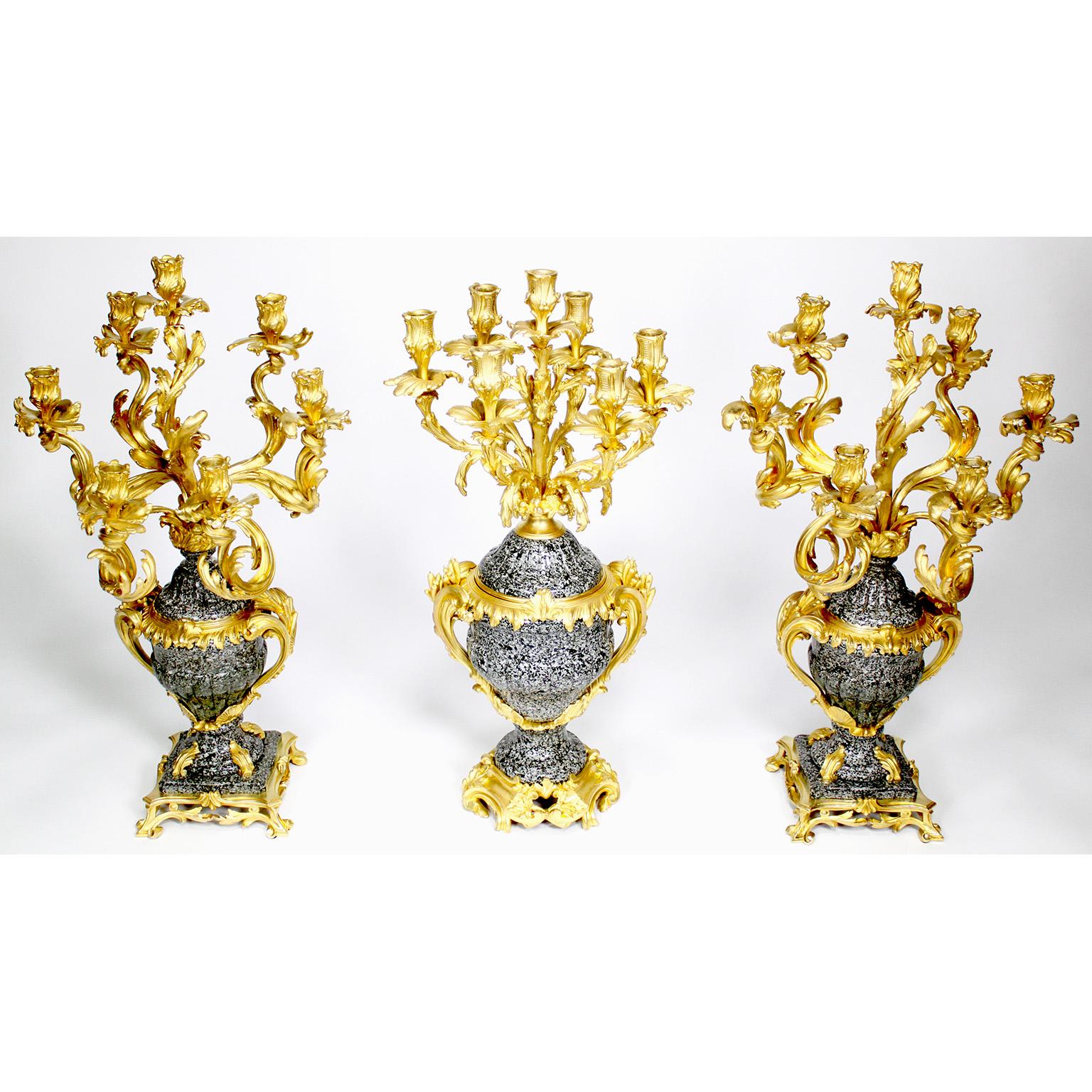 Raffinatissimo set di candelabri a tre pezzi in stile Luigi XV del XIX/20° secolo, con montatura in ormolu e urna in granito screziato, a sette luci. Le urne sagomate sono simili nelle variazioni agli esempi, originariamente realizzati per gli