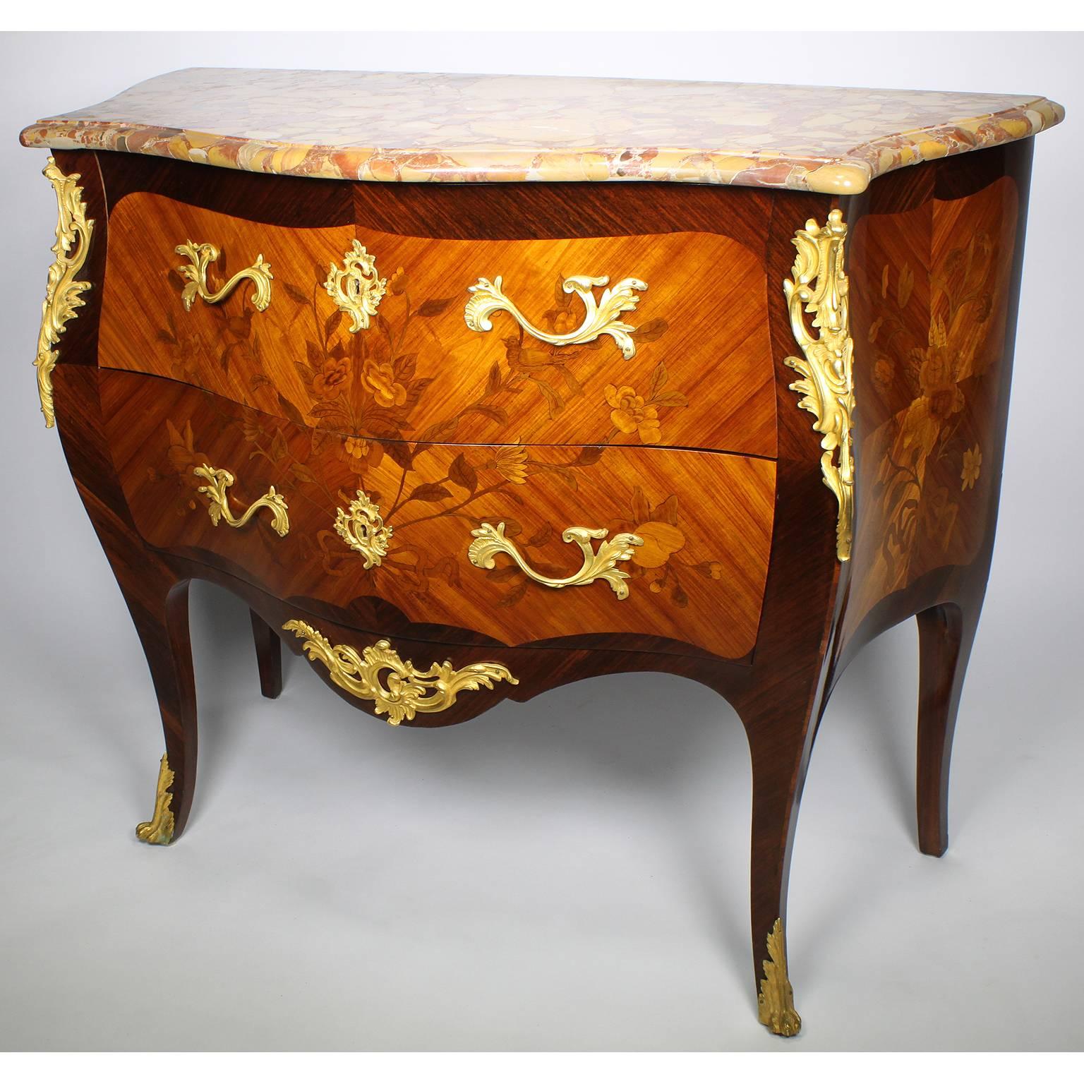 A fine French 19th-20th century Louis XV style tulipwood floral marquetry and gilt bronze mounted two drawer bombé petit commode. The serpentine shaped commode with two front drawers, each with a pair of scrolled floral ormolu handles and a