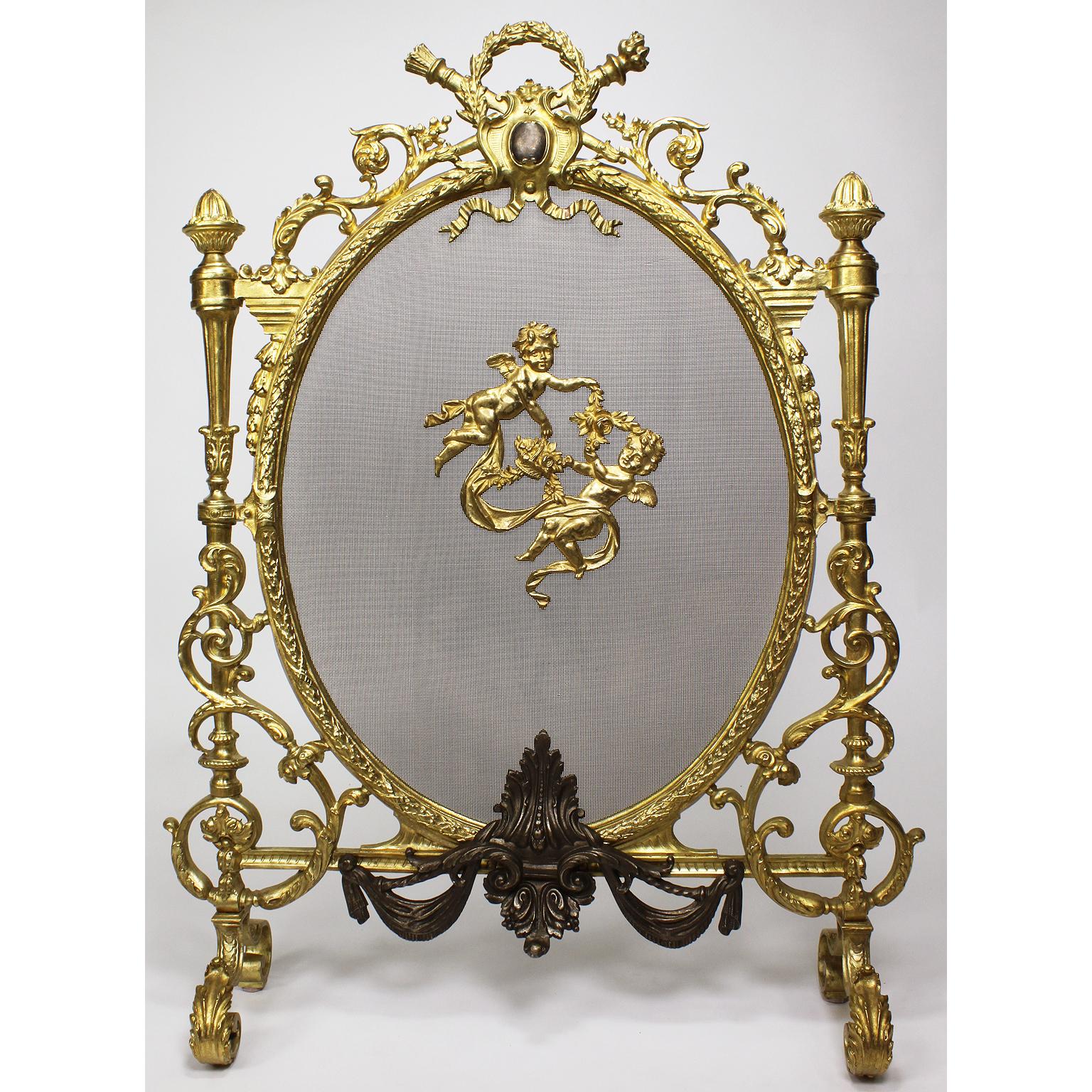 A French 19th-20th century 'Belle Époque' Louis XV style gilt and patinated bronze fireplace screen. The ornately decorated oval screen, supported with a pair a of finial columns, surmounted with floral acanthus, leaves, ribbons and draped swags.
