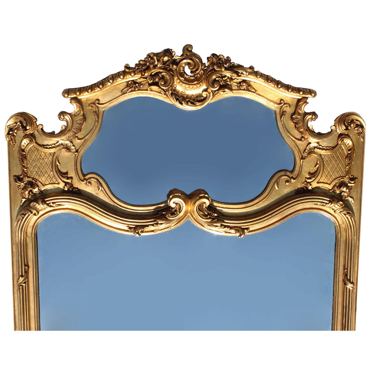 A large French 19th-20th century Belle Époque Louis XV style giltwood carved trumeau mirror frame. The elongated carved frame crowned with a scrolled finial surmounted with flowers, shells and acanthus, the top panel fitted with a mirror plate, the