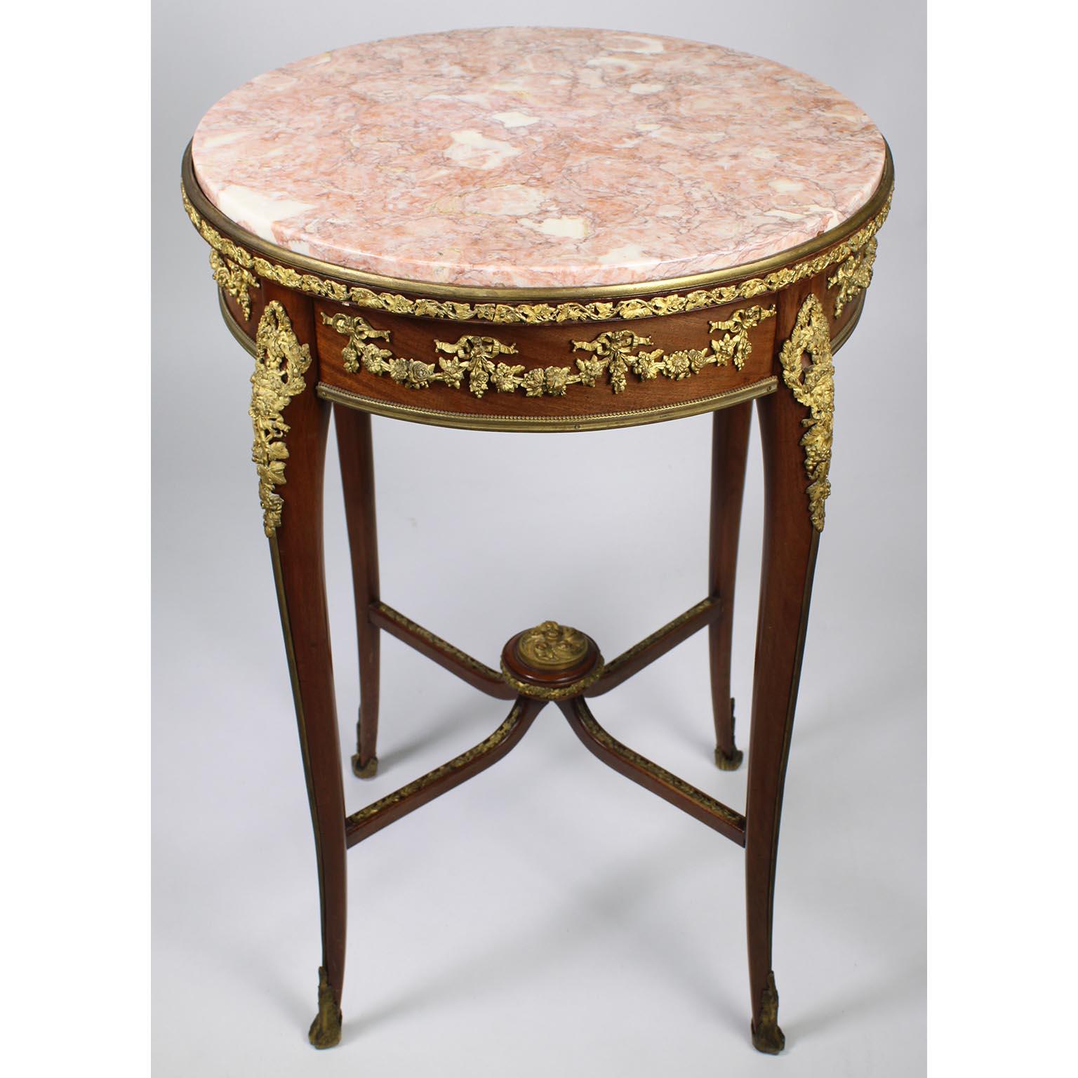 Table d'appoint circulaire en acajou et bronze doré (Ormolu) de la Belle Époque, avec plateau en marbre, attribuée à François Linke (1855-1946). La table d'appoint à un seul tiroir est ornée d'un plateau rond en marbre rose veiné surmonté d'une